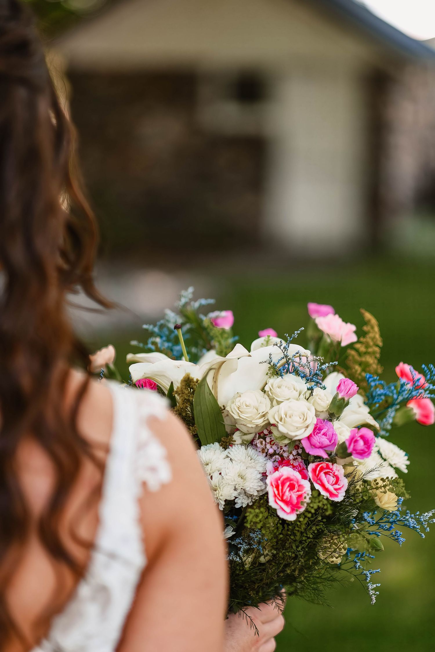 Colorful bridal bouquet featuring pink roses, white flowers, and blue accents.
