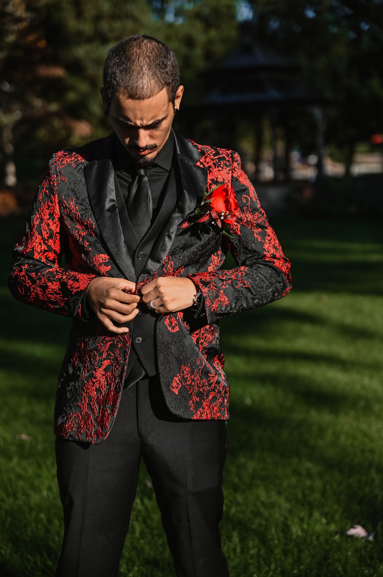 Person adjusting a stylish black and red floral patterned suit jacket outdoors.
