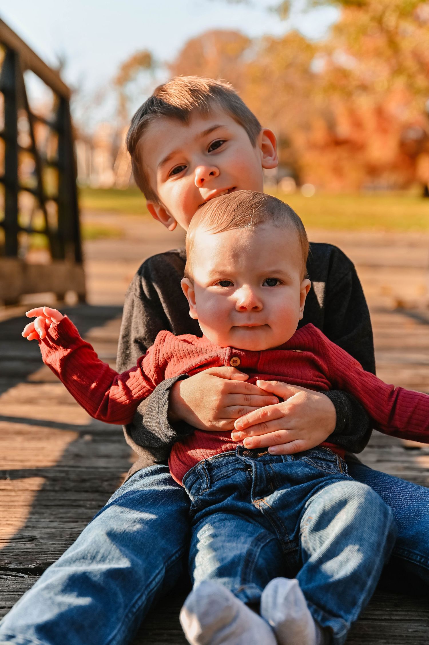 Young child relaxing on a wooden deck during a sunny autumn day.