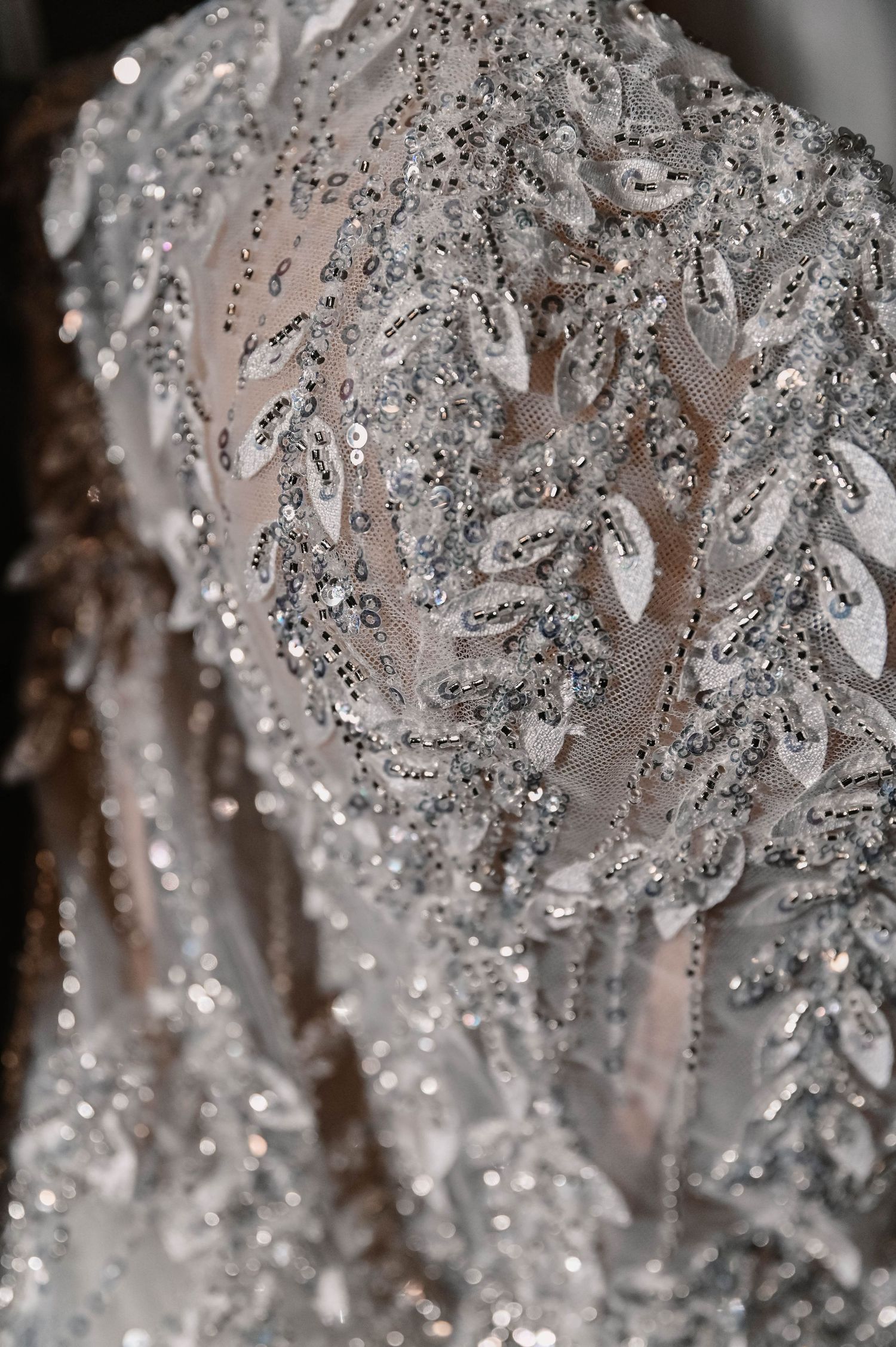 Close-up detail of intricate beading and crystals on wedding dress fabric.