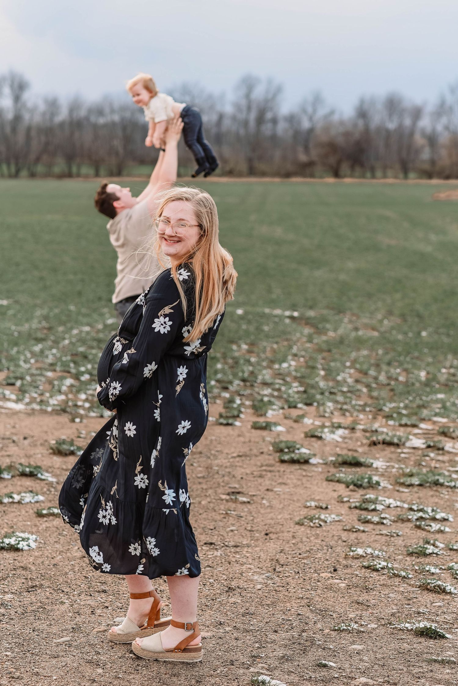 Person in floral dress dances joyfully in an open field.