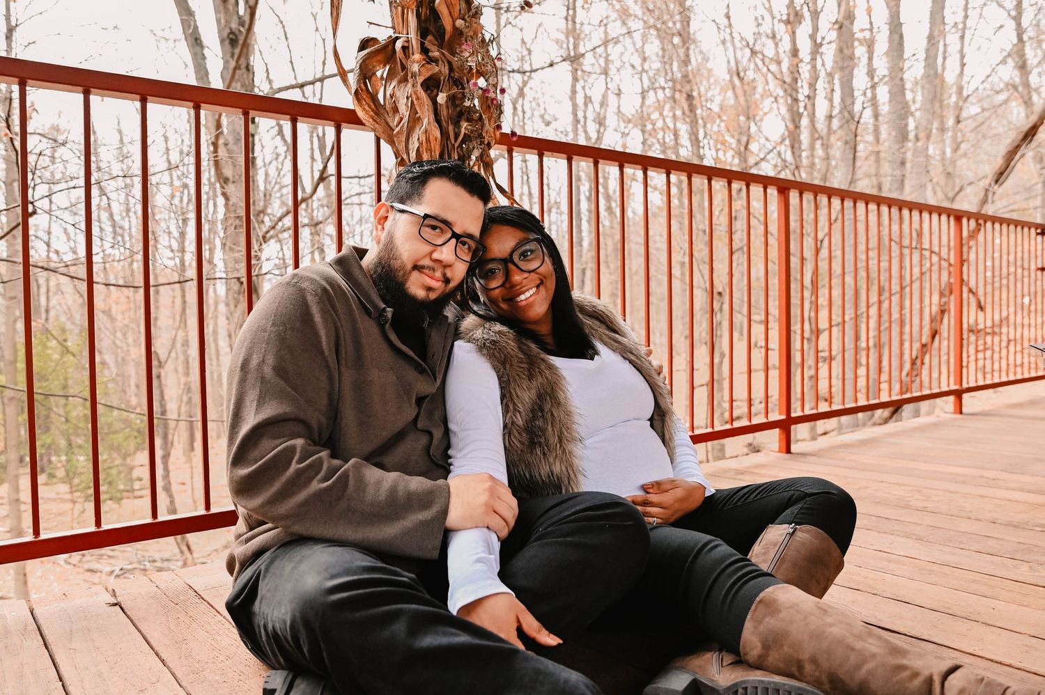 A couple relaxes together on a rustic deck in a natural outdoor setting.