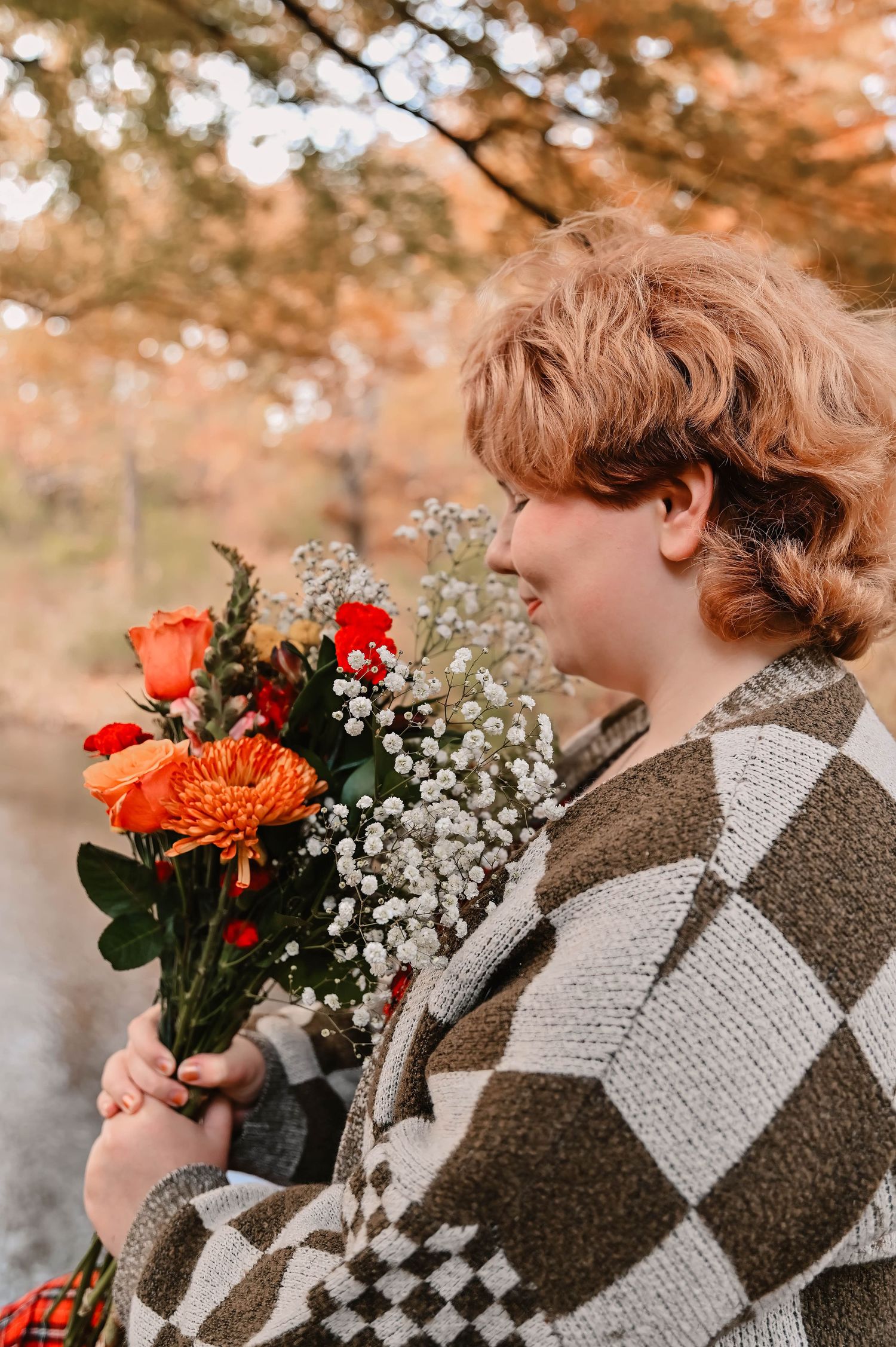 Cozy checkered sweater paired with orange and white flowers in an autumn setting.