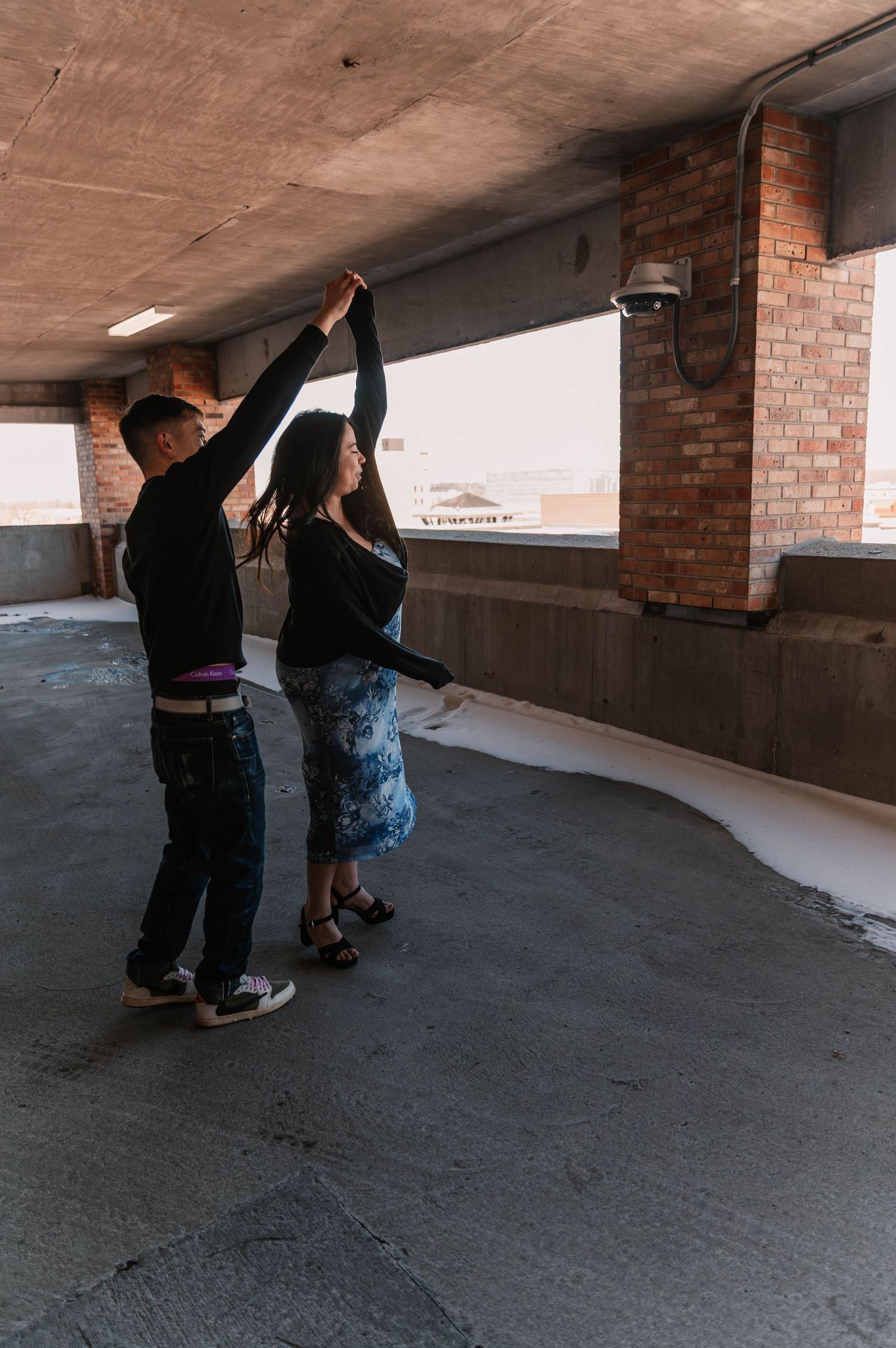 Dancing sequence in an urban parking structure with brick walls.