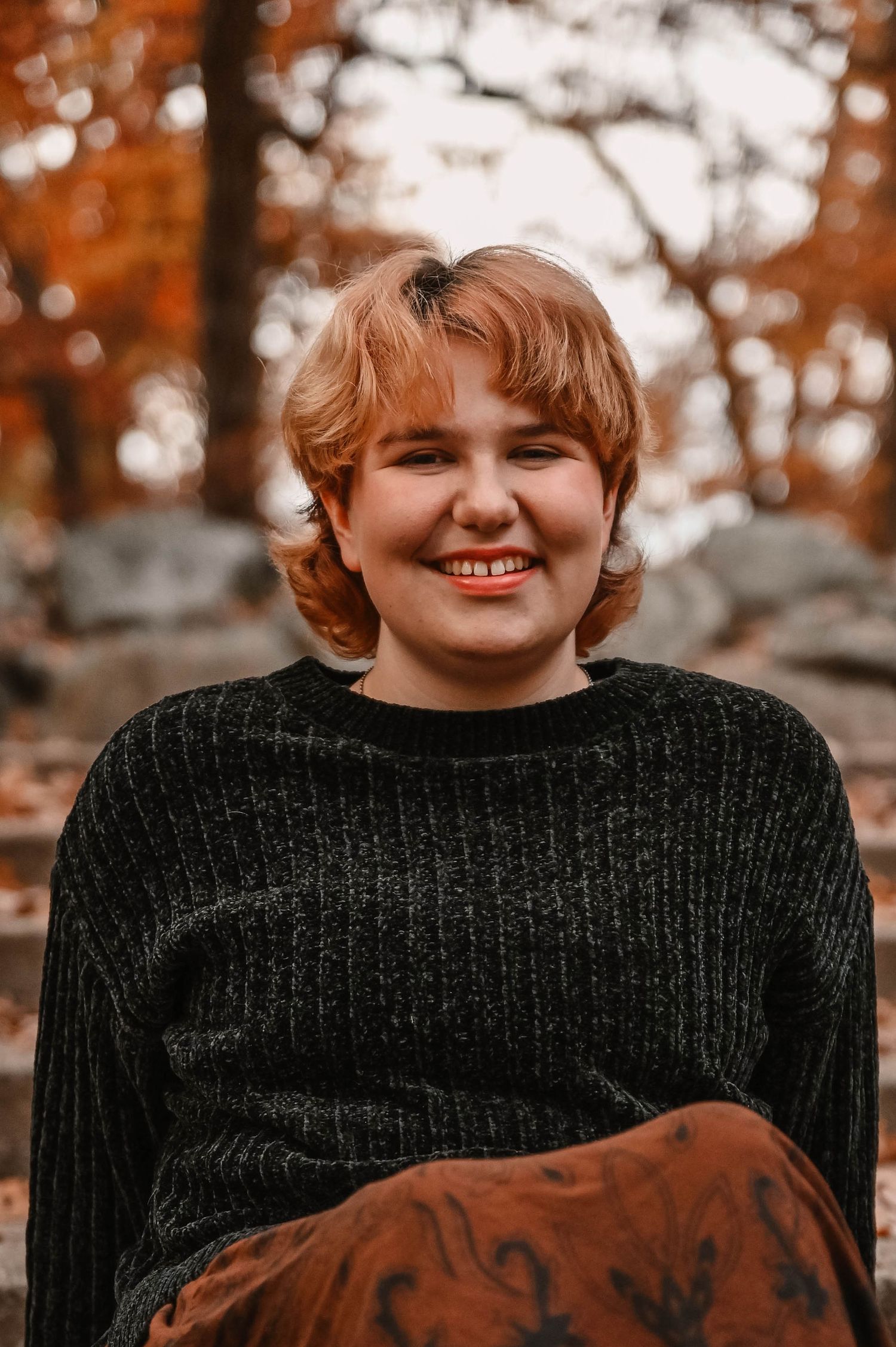 Casual autumn portrait featuring black sweater and decorative blanket outdoors.