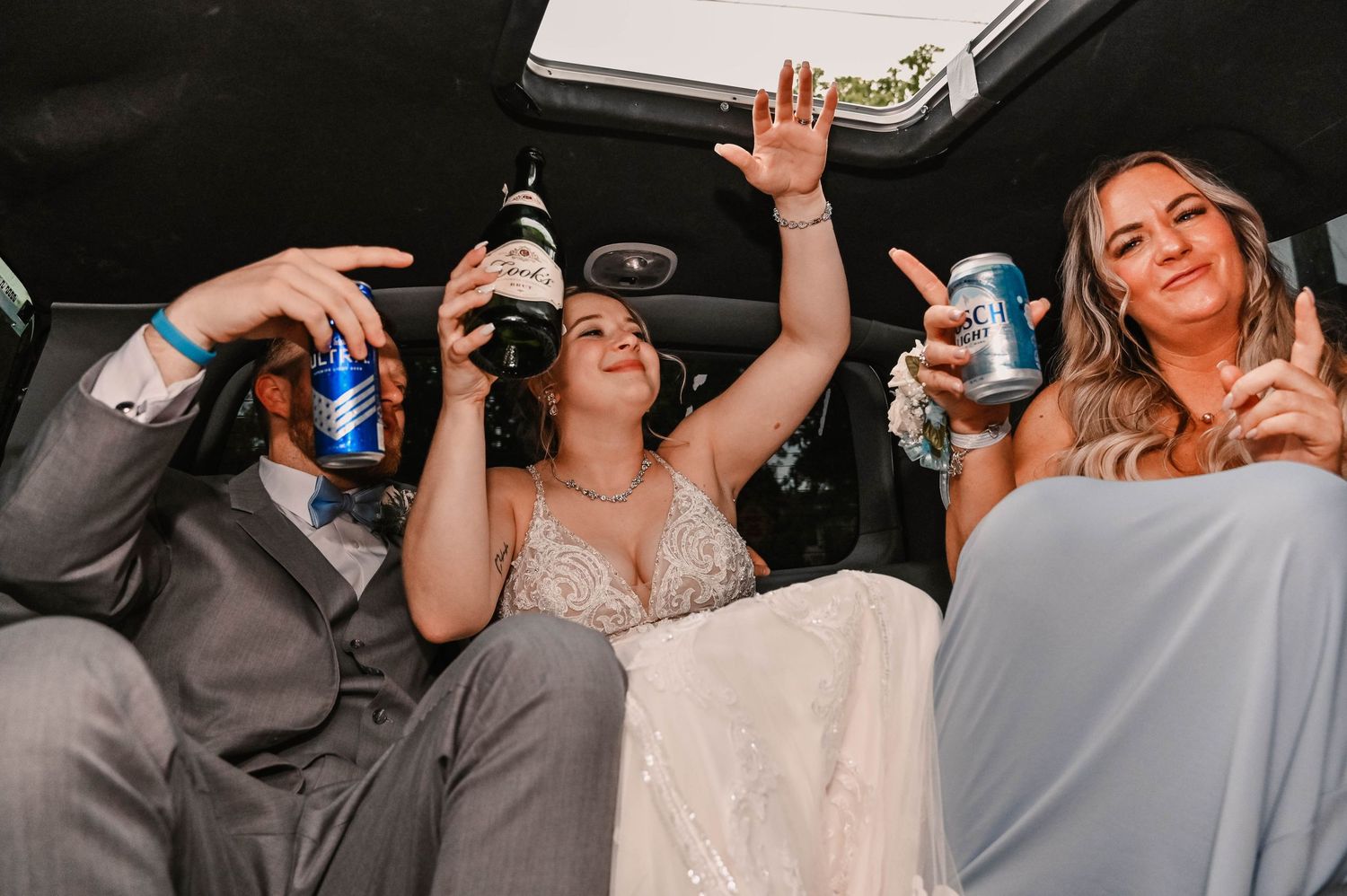 Wedding party celebrates in a limo drinking and having fun together.