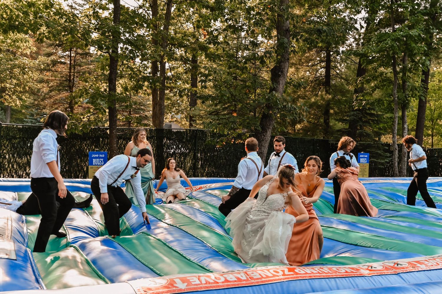 Wedding guests having fun bouncing on an inflatable bounce house at an outdoor celebration.