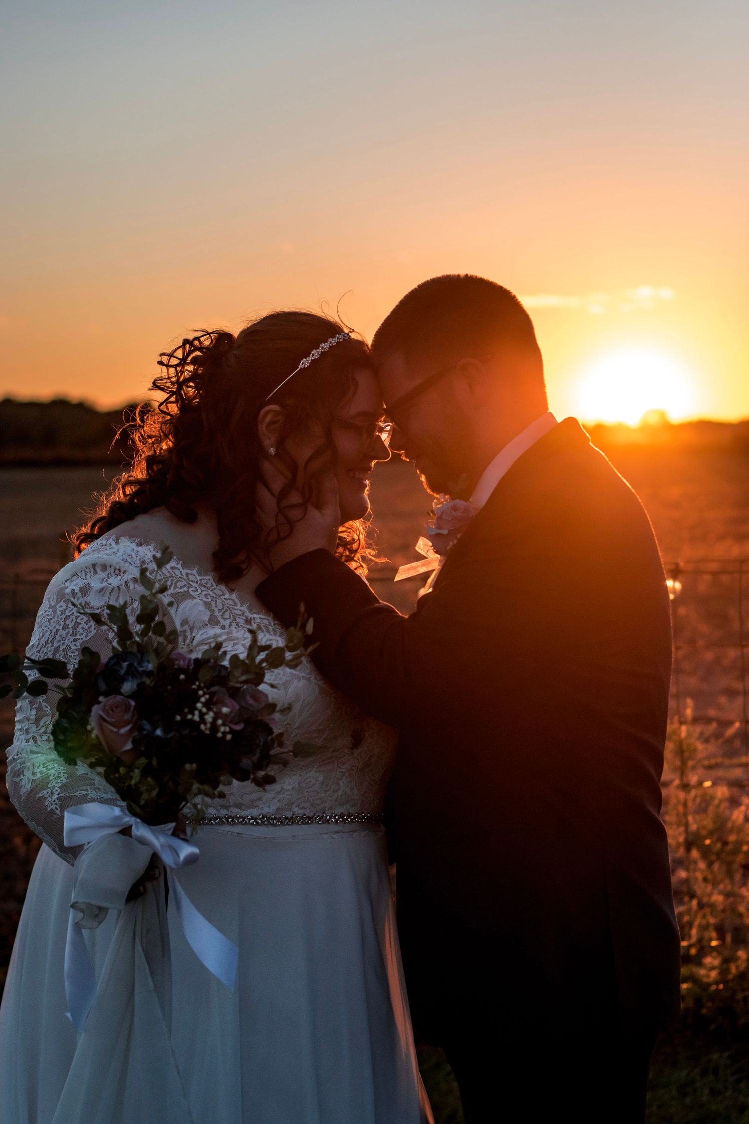 Romantic silhouette of newlyweds embracing at sunset with golden light.