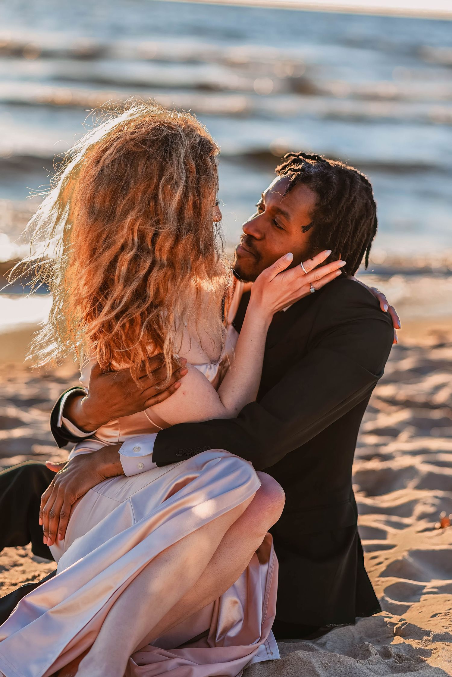 Couple sharing intimate moments on a sandy beach at sunset.
