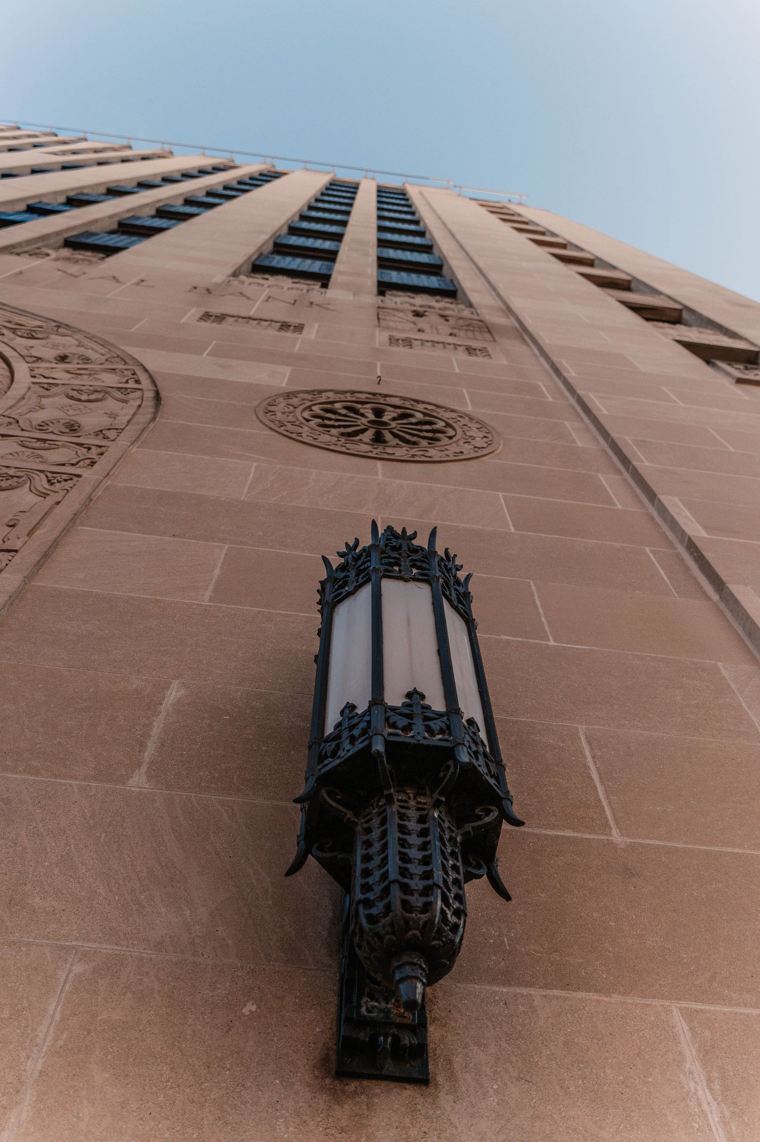 Ornate black iron wall sconces mounted on a beige stone building exterior.