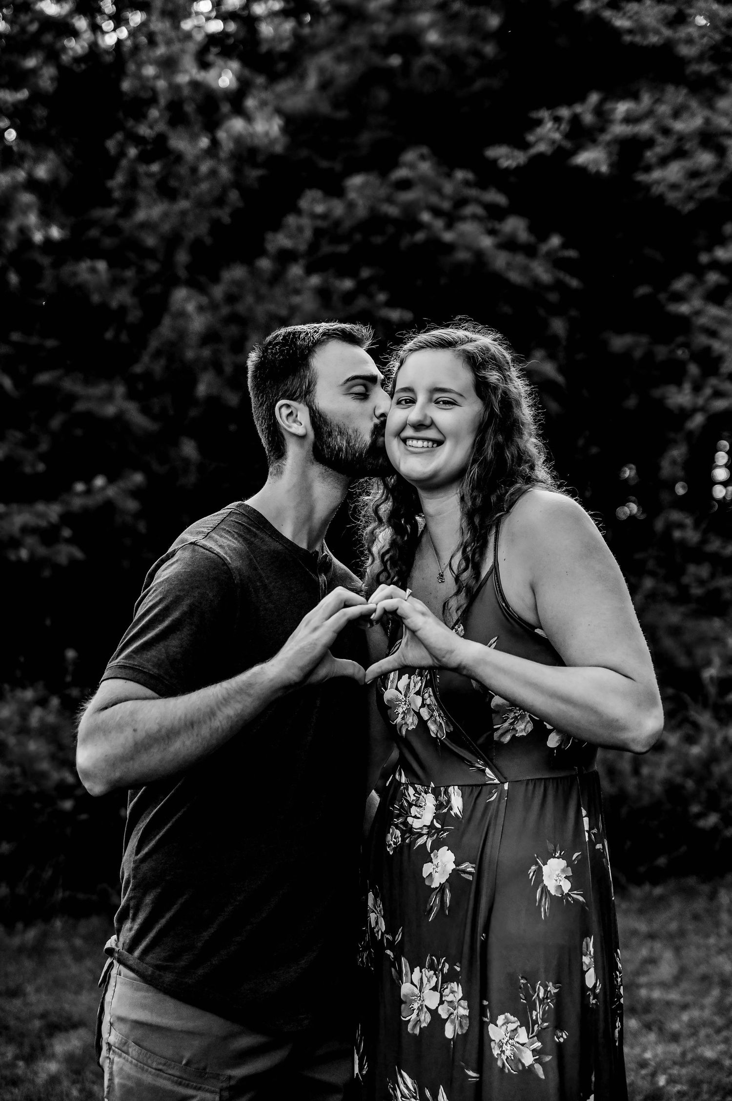 Black and white photo of couple sharing intimate moment outdoors.