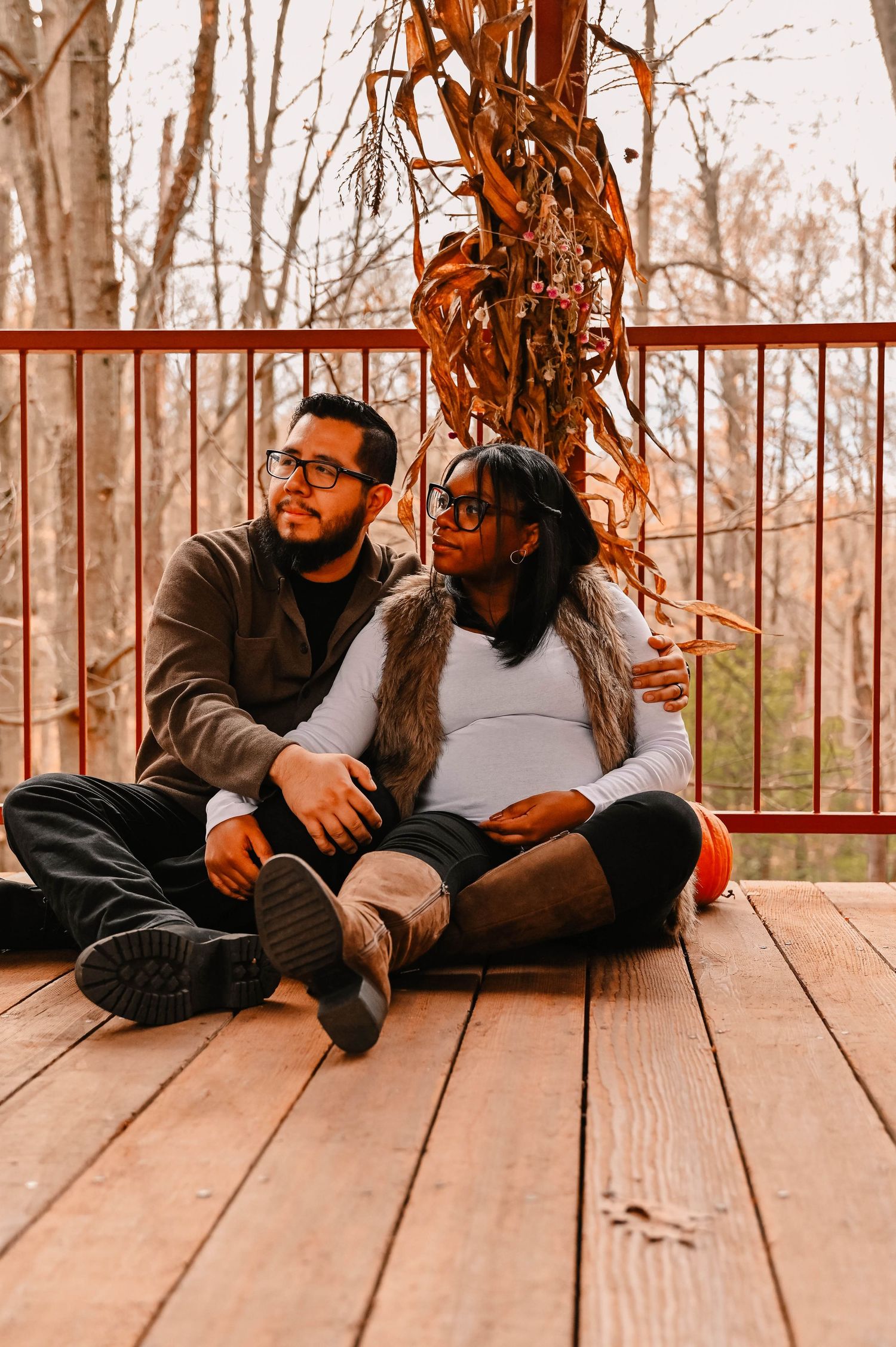 Two people share a tender moment while lying on wooden deck boards in autumn.