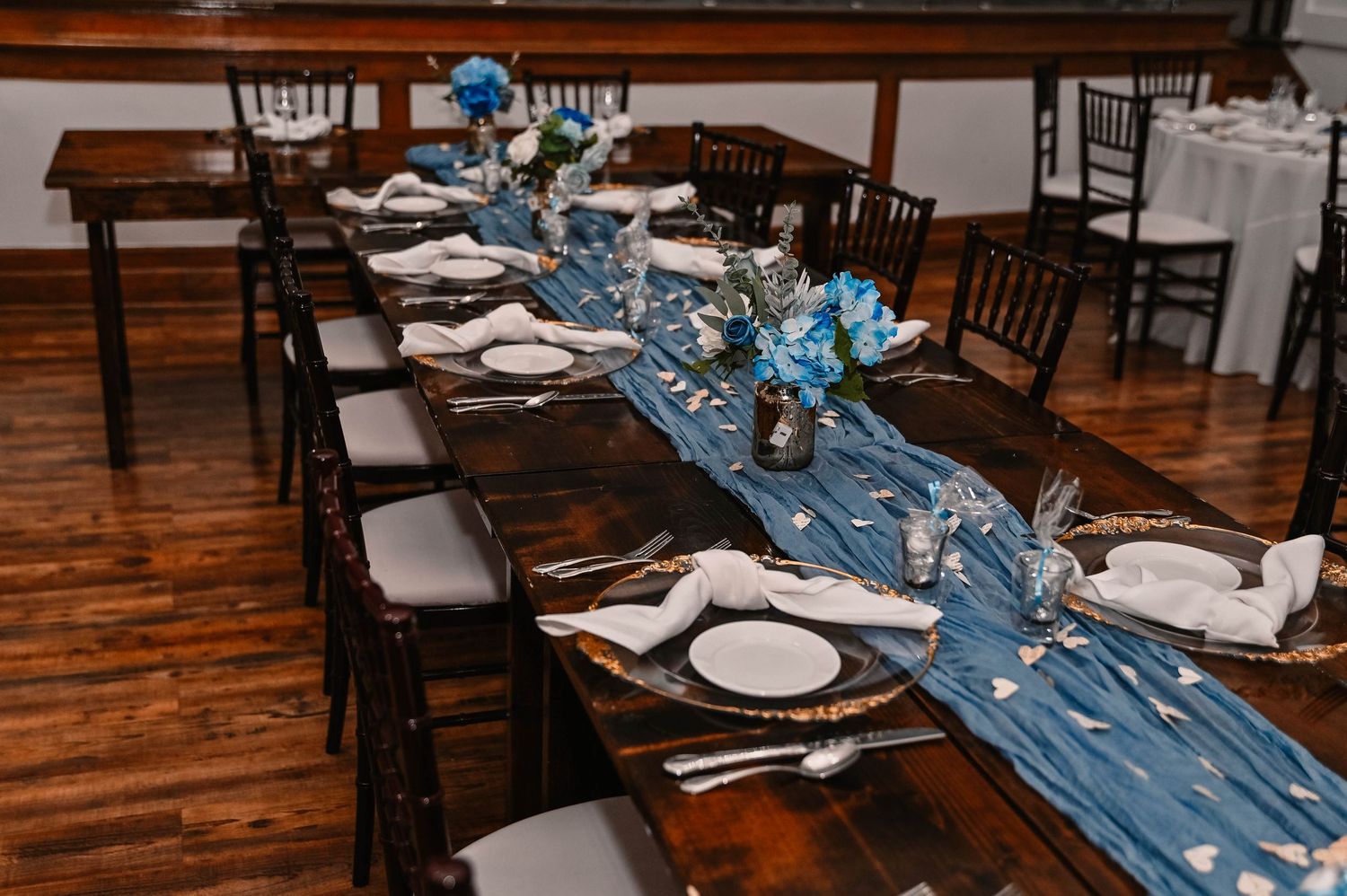 Elegant wedding reception tables set with blue runners and place settings.