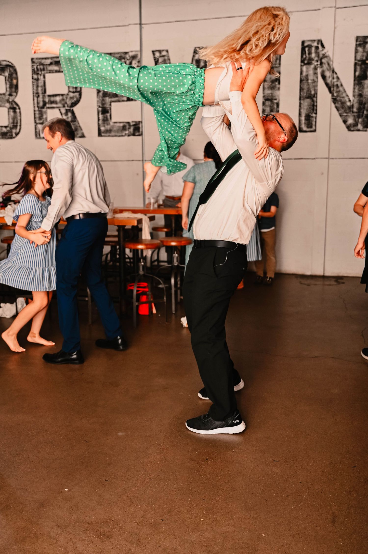 Dancers perform energetic swing dance moves on a dark indoor dance floor.