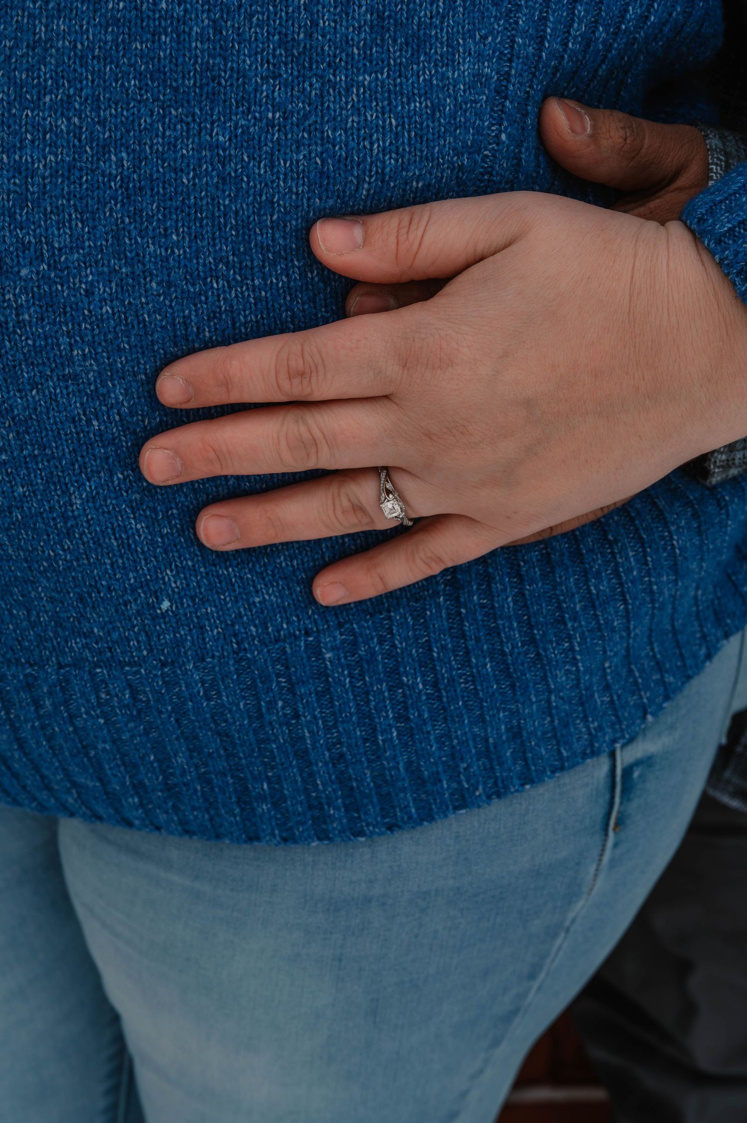 Close-up sequence of hand with engagement ring against blue sweater.