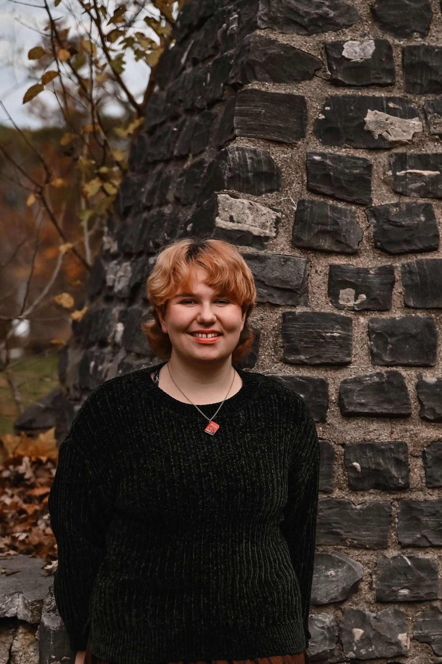 Black stone wall creates contrast with autumn-themed portrait.