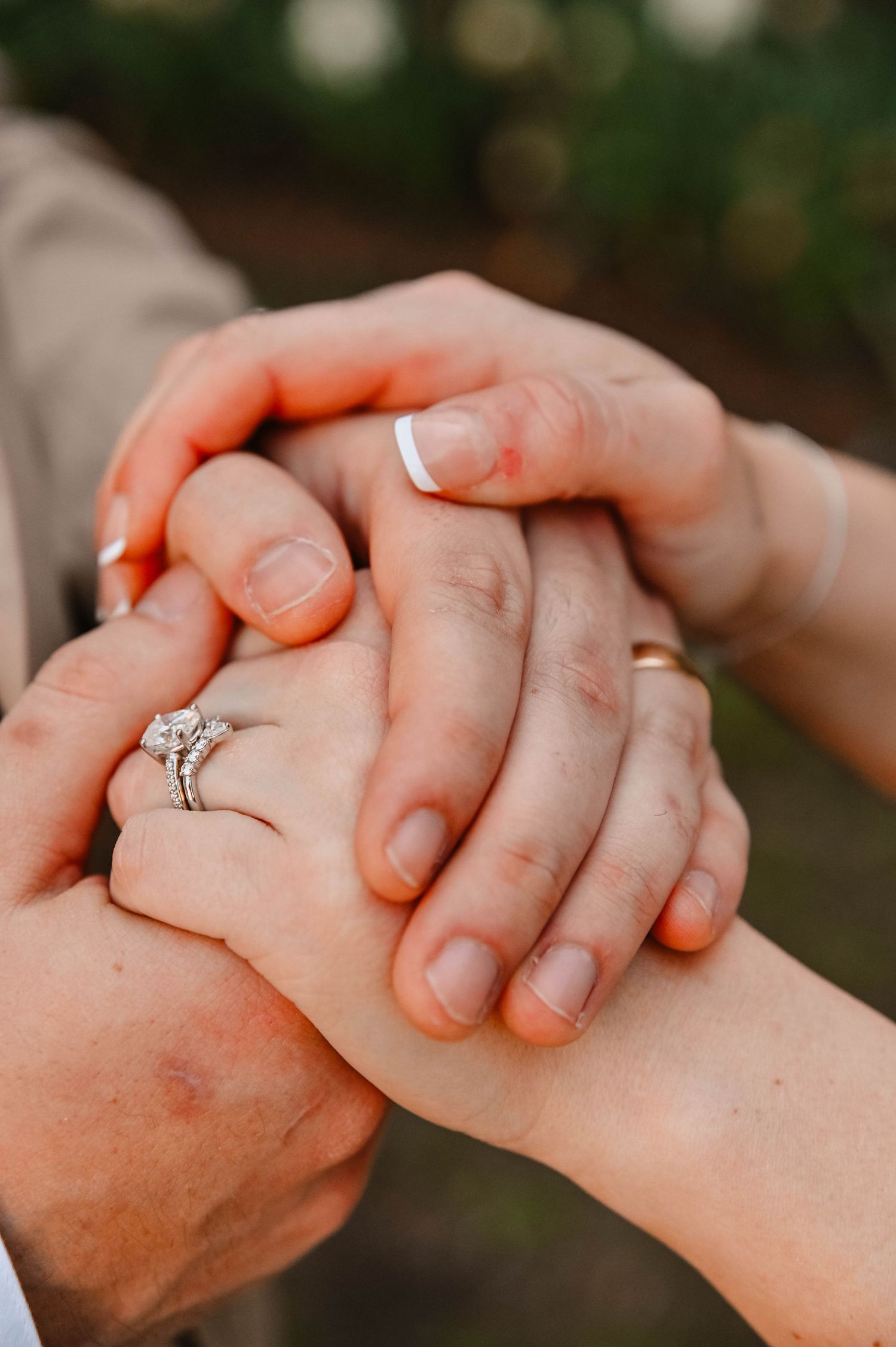 Close up of hands holding with engagement ring visible.