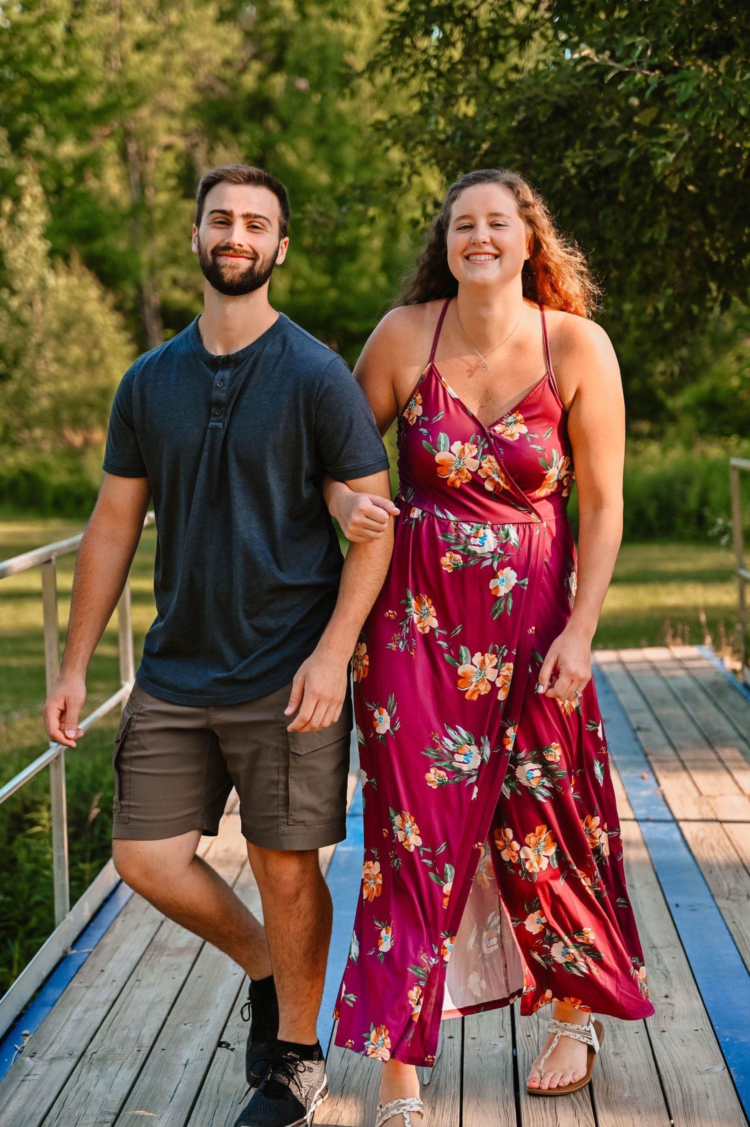 Couple laughing together on wooden deck during golden hour photoshoot.