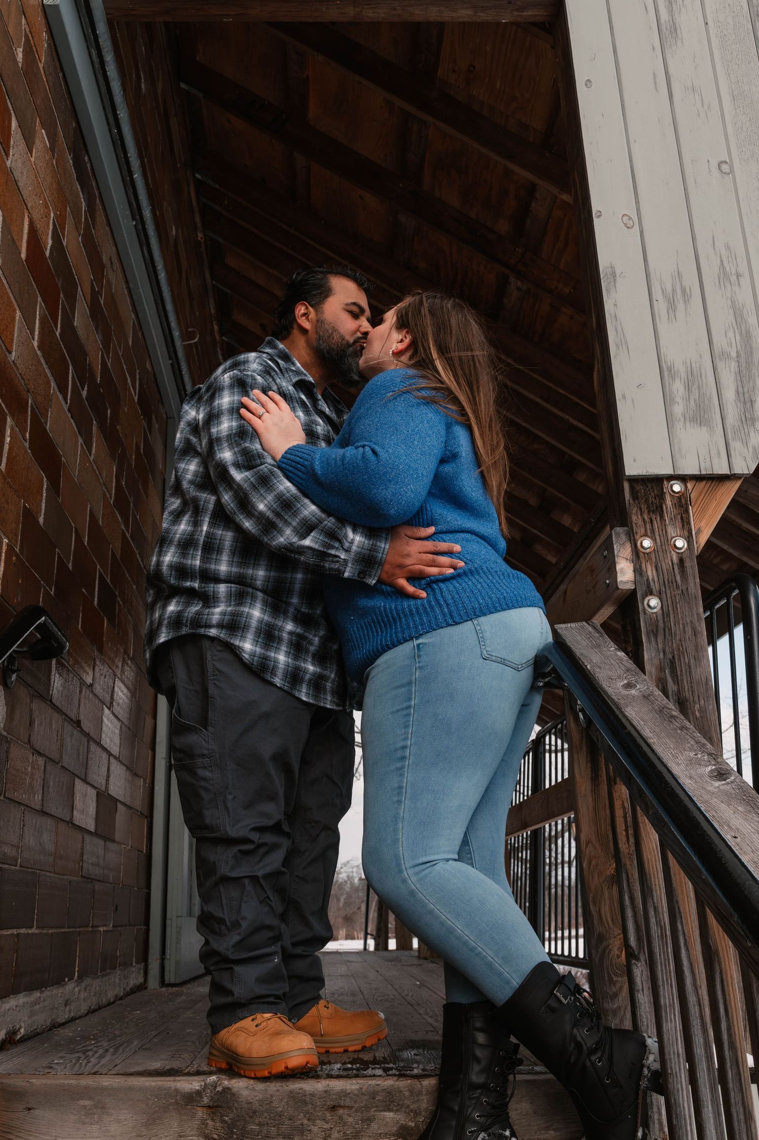 Romantic couple photos captured in a rustic wooden stairwell setting.