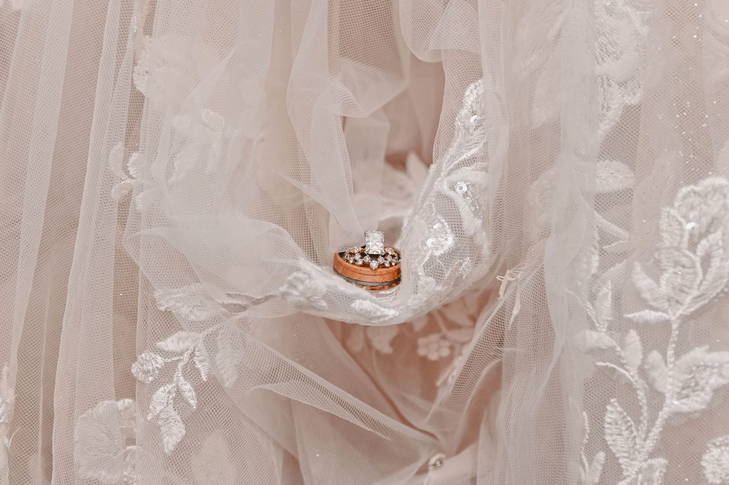 Wedding rings nestled in delicate white lace fabric creating an elegant bridal detail shot.