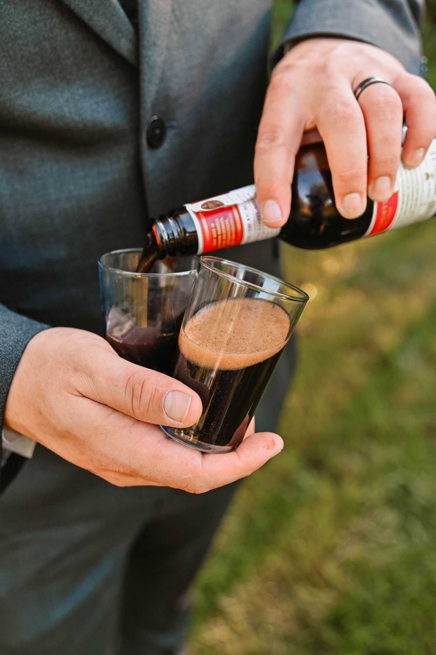 Hands pouring a dark liquid from a bottle into a glass in a sequence of shots.