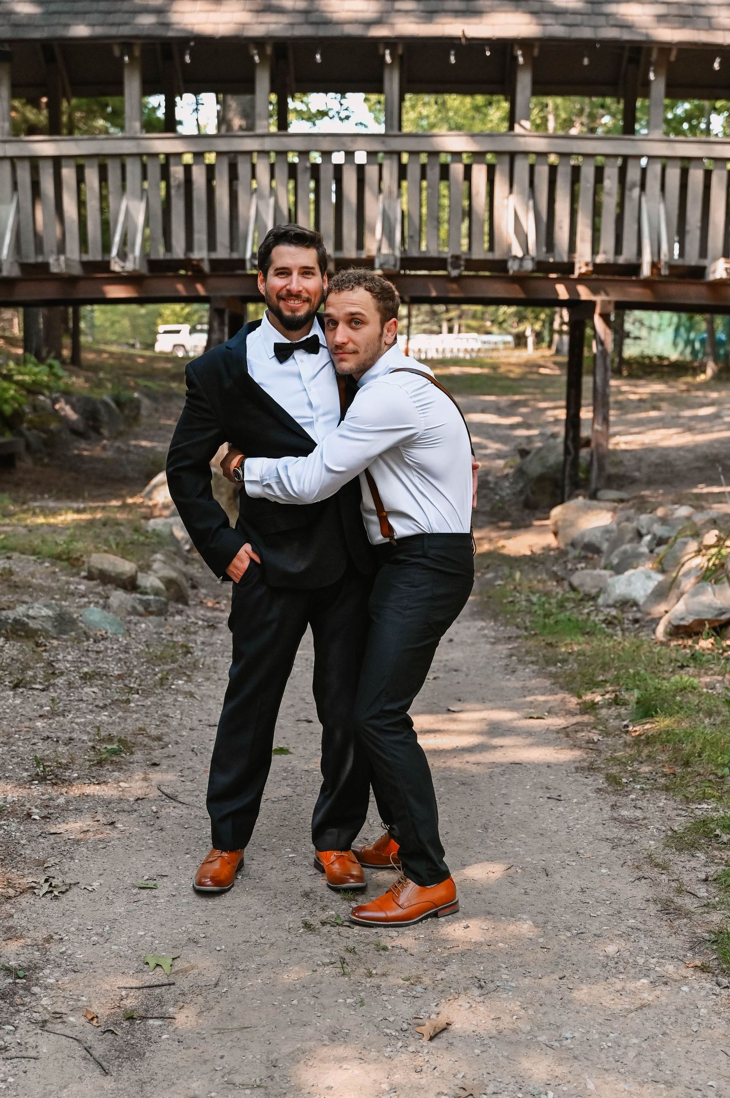 Two people in formal wear striking playful poses outdoors.