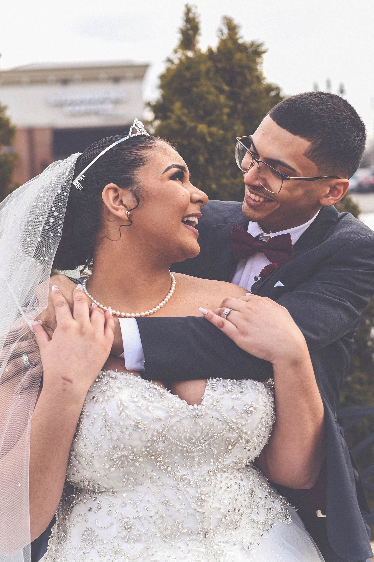 Newlyweds sharing a tender moment in their wedding attire outdoors.