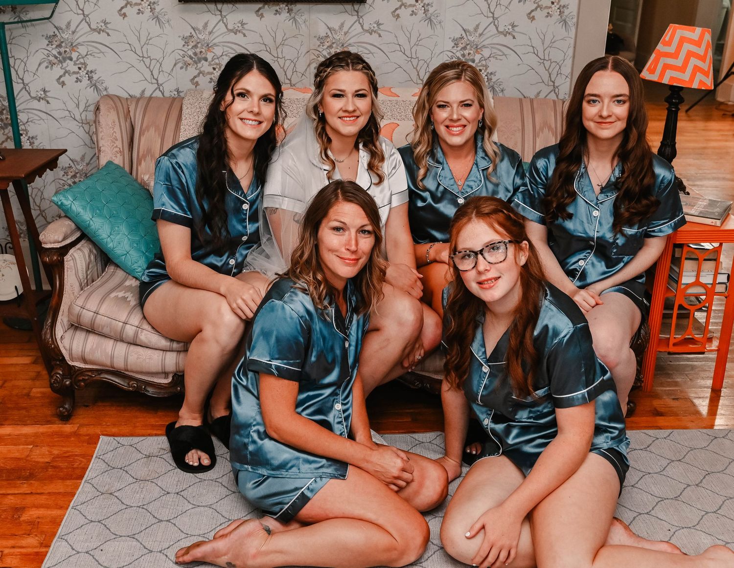 Group wearing matching blue robes relaxing on floor during pre-wedding preparations.