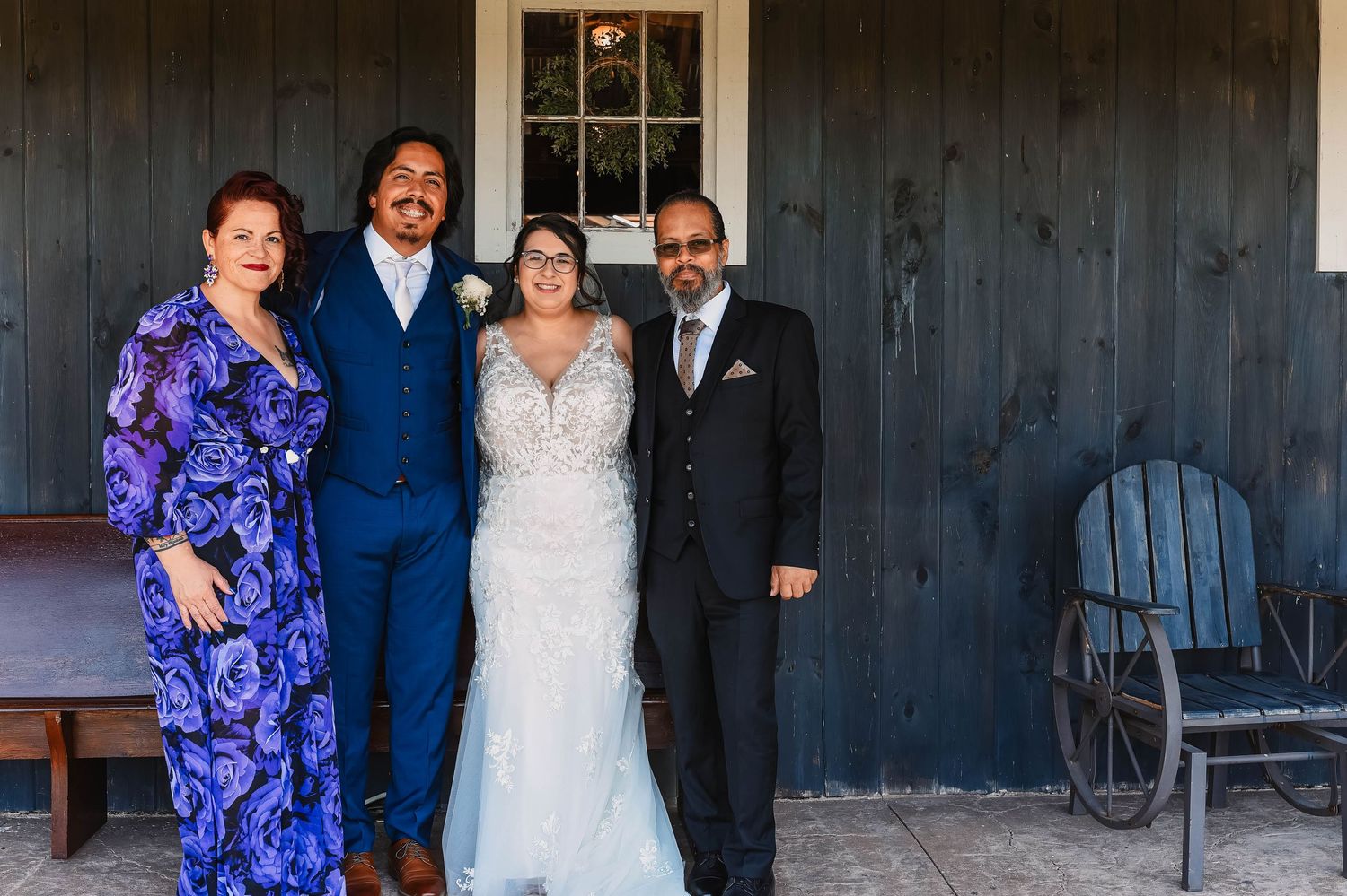 Group wedding photos taken in front of a charming rustic wooden building exterior.