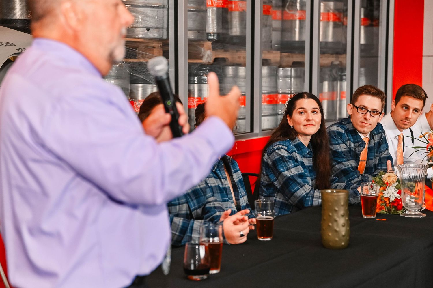 Guests raise glasses in celebration during wedding reception at brewery.