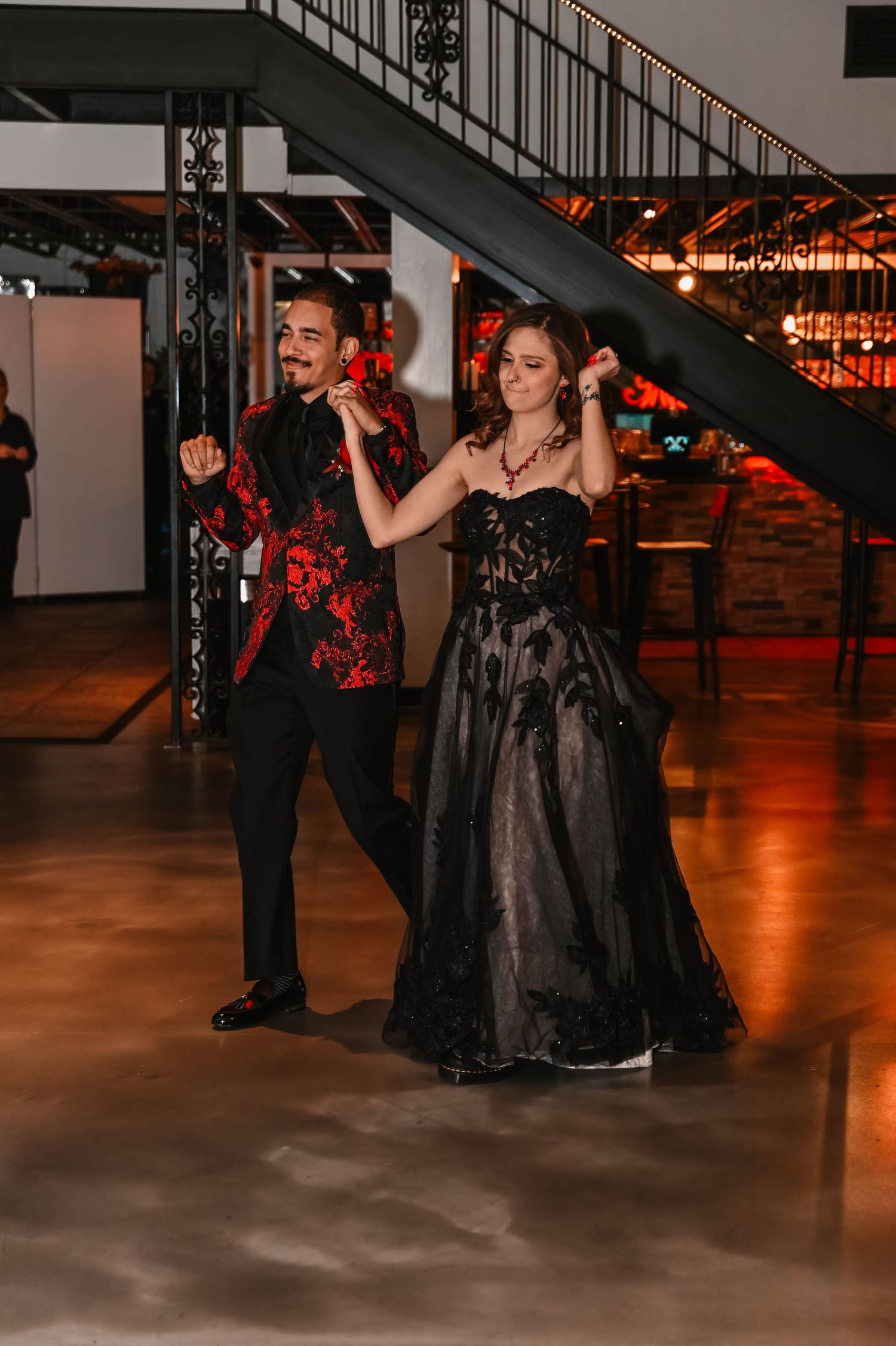 Wedding party dancing and celebrating in black and red formal attire.