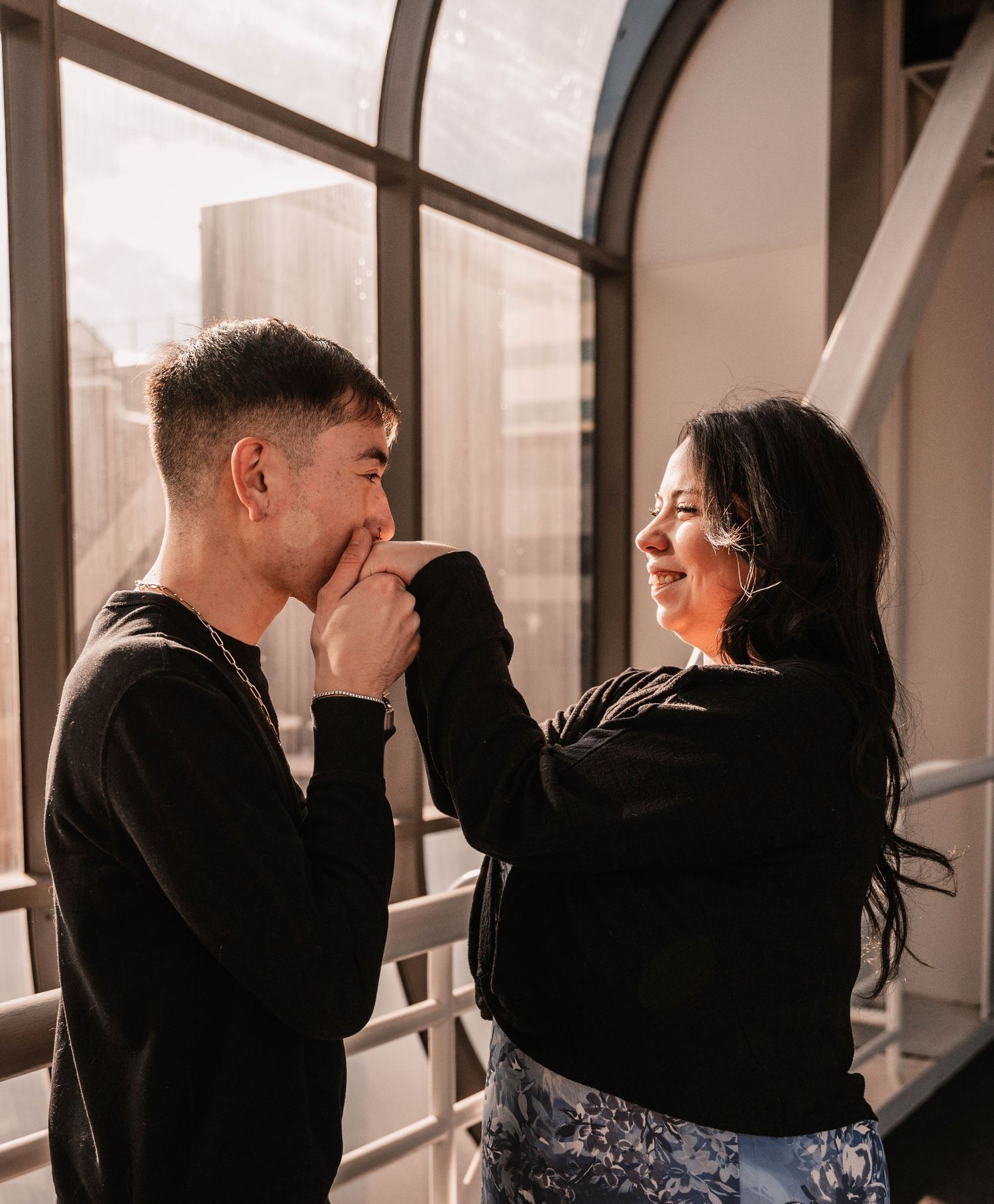 Romantic sequence of a couple sharing intimate moments by large windows.