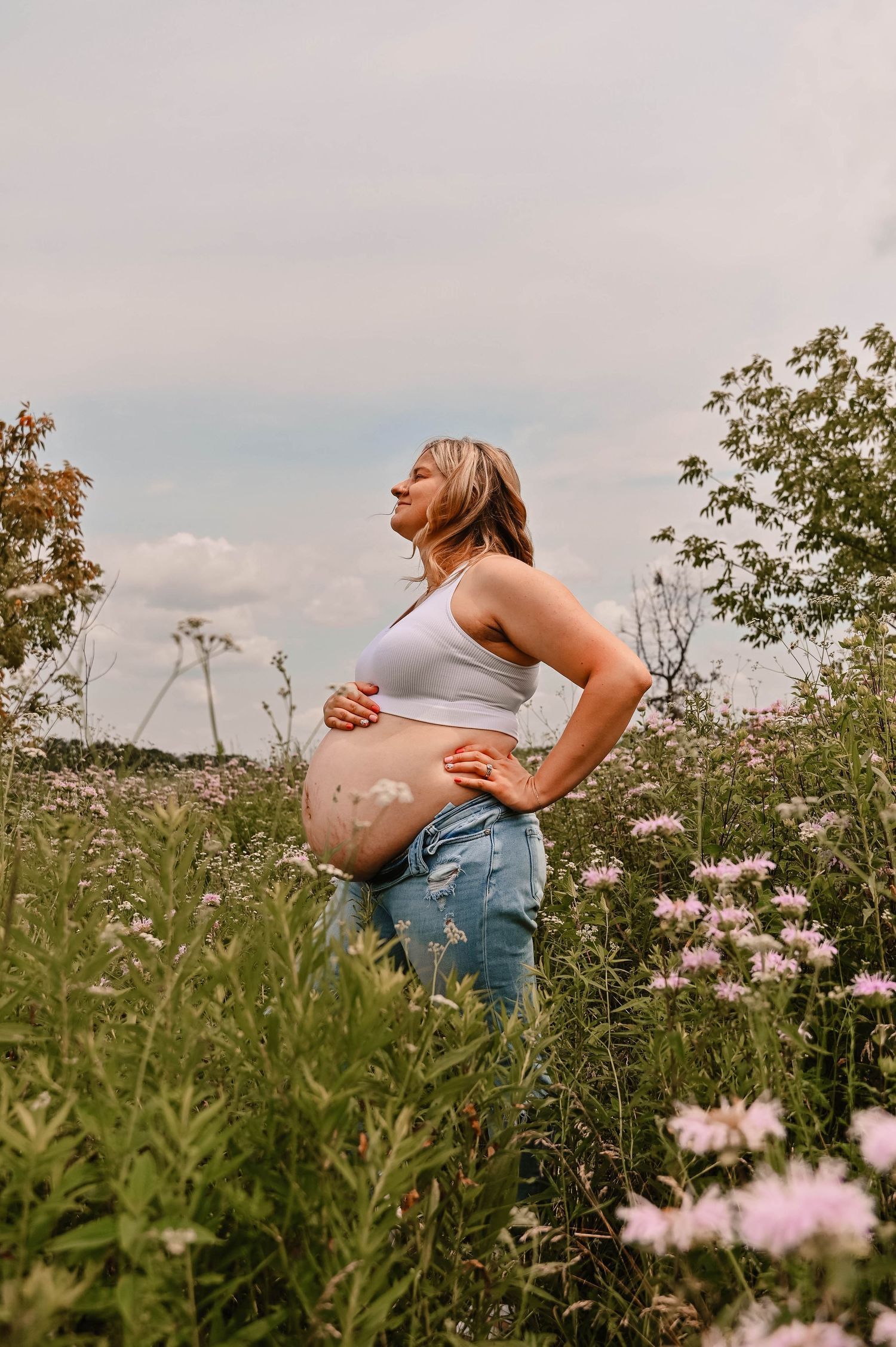 Maternity photos taken in a wildflower field during golden hour.