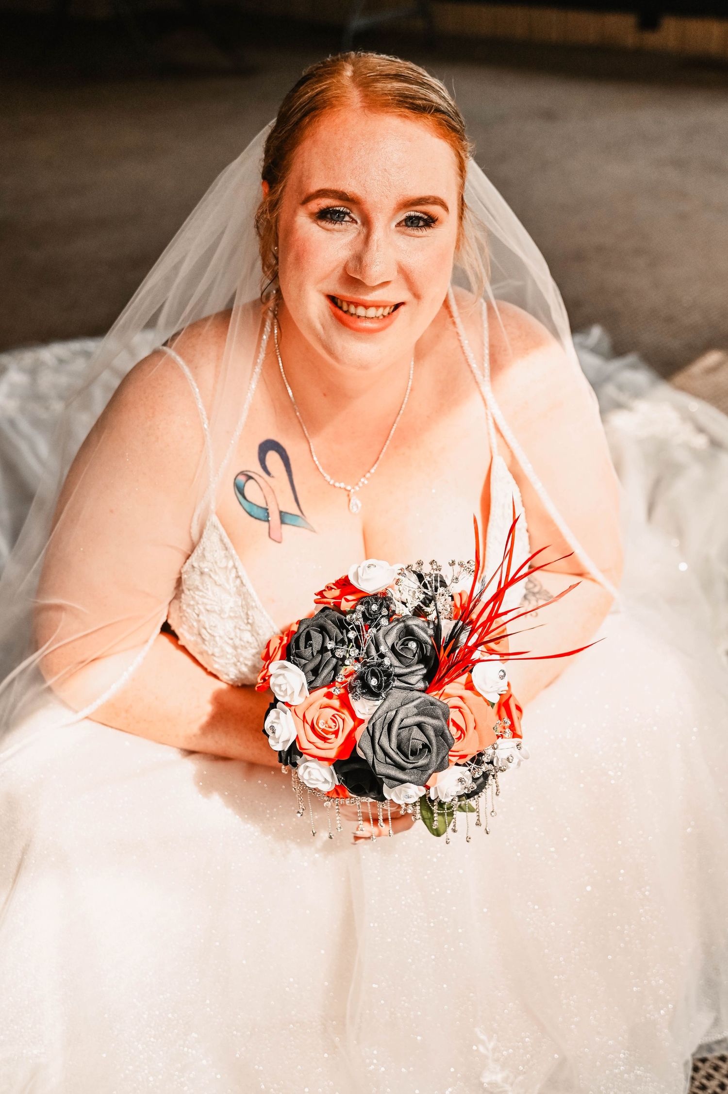 A wedding portrait featuring a bouquet of red, black and white roses.