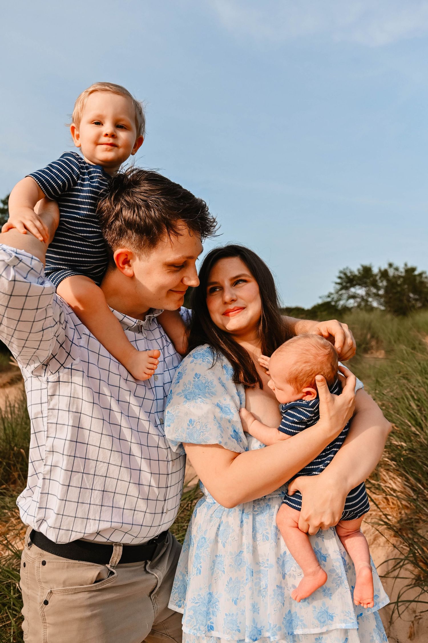 Young family enjoying a sunny day outdoors with their children in matching striped outfits.