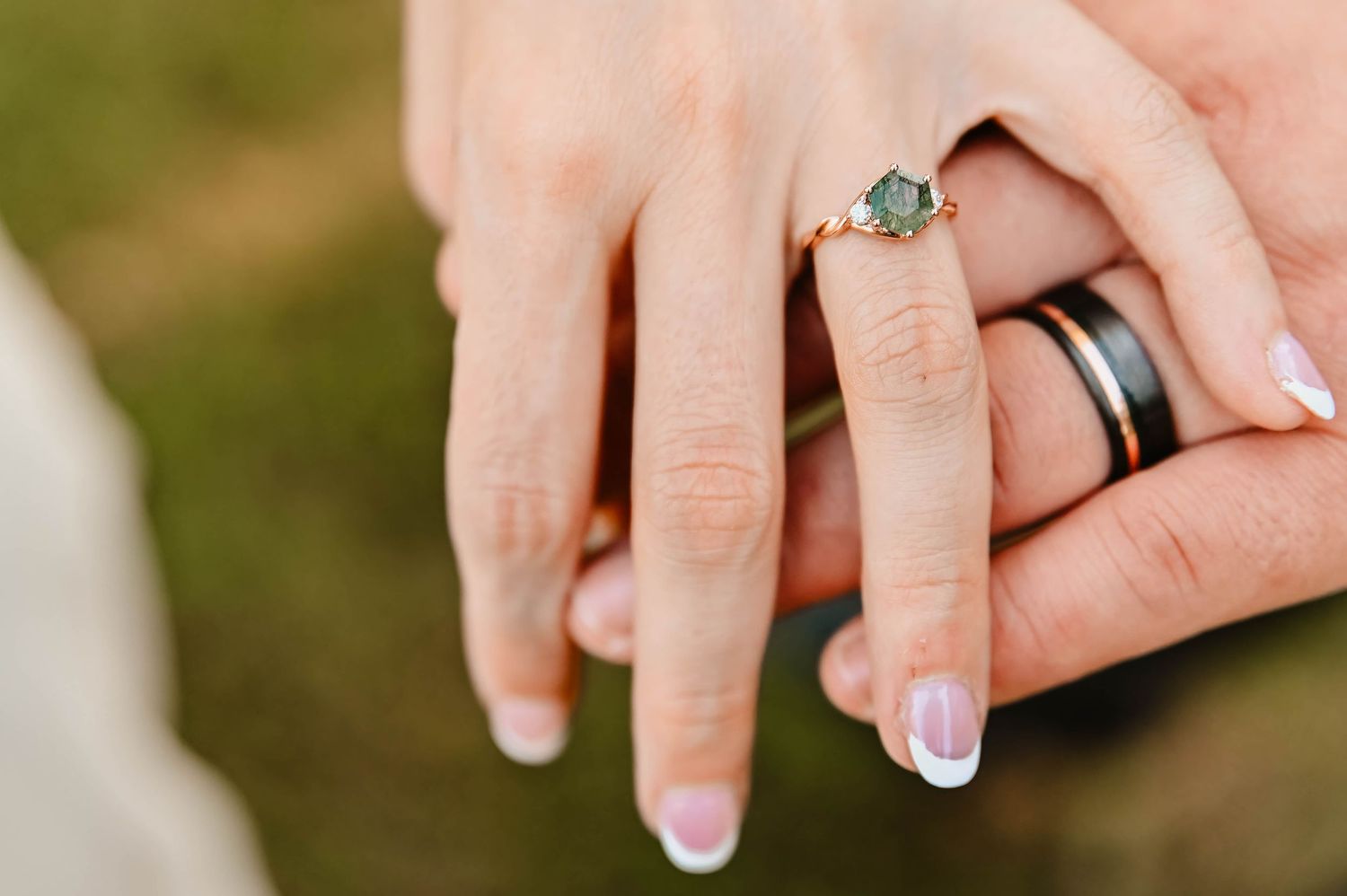 Close-up of wedding rings and hands with French manicure.