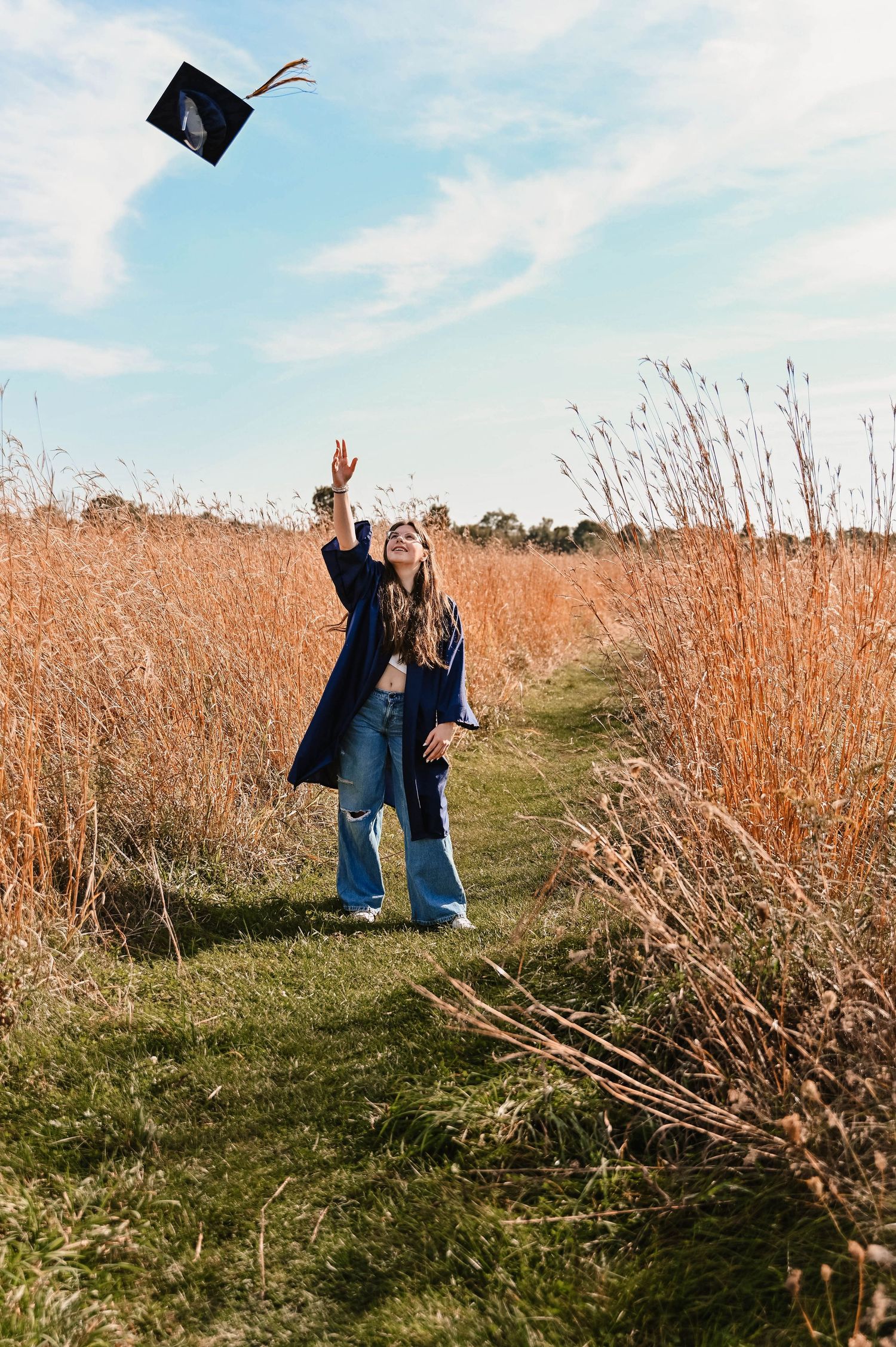 Graduation celebration photos in a field of tall grass under blue skies.