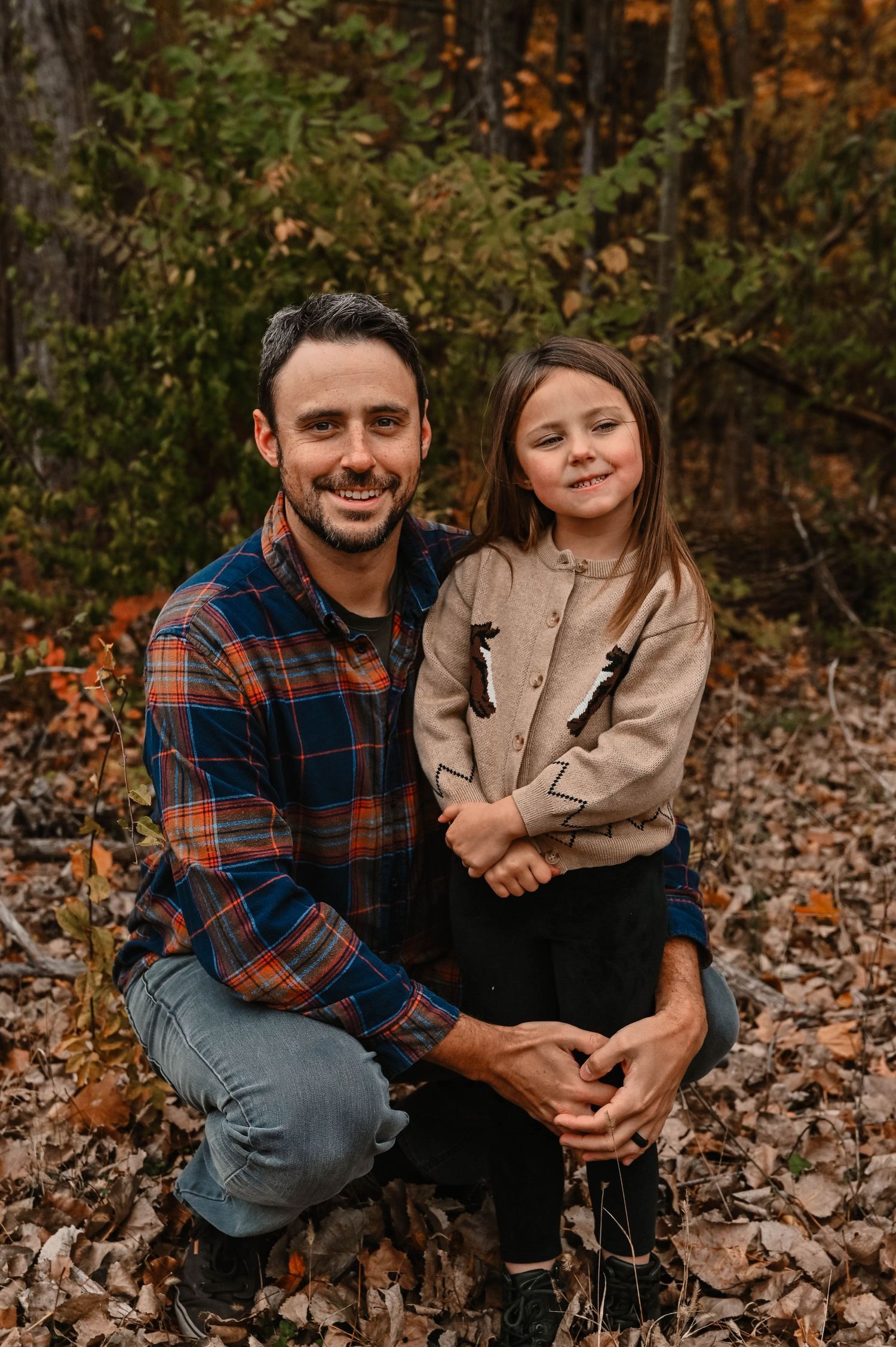 Casual outdoor family portrait with autumn leaves and natural lighting.