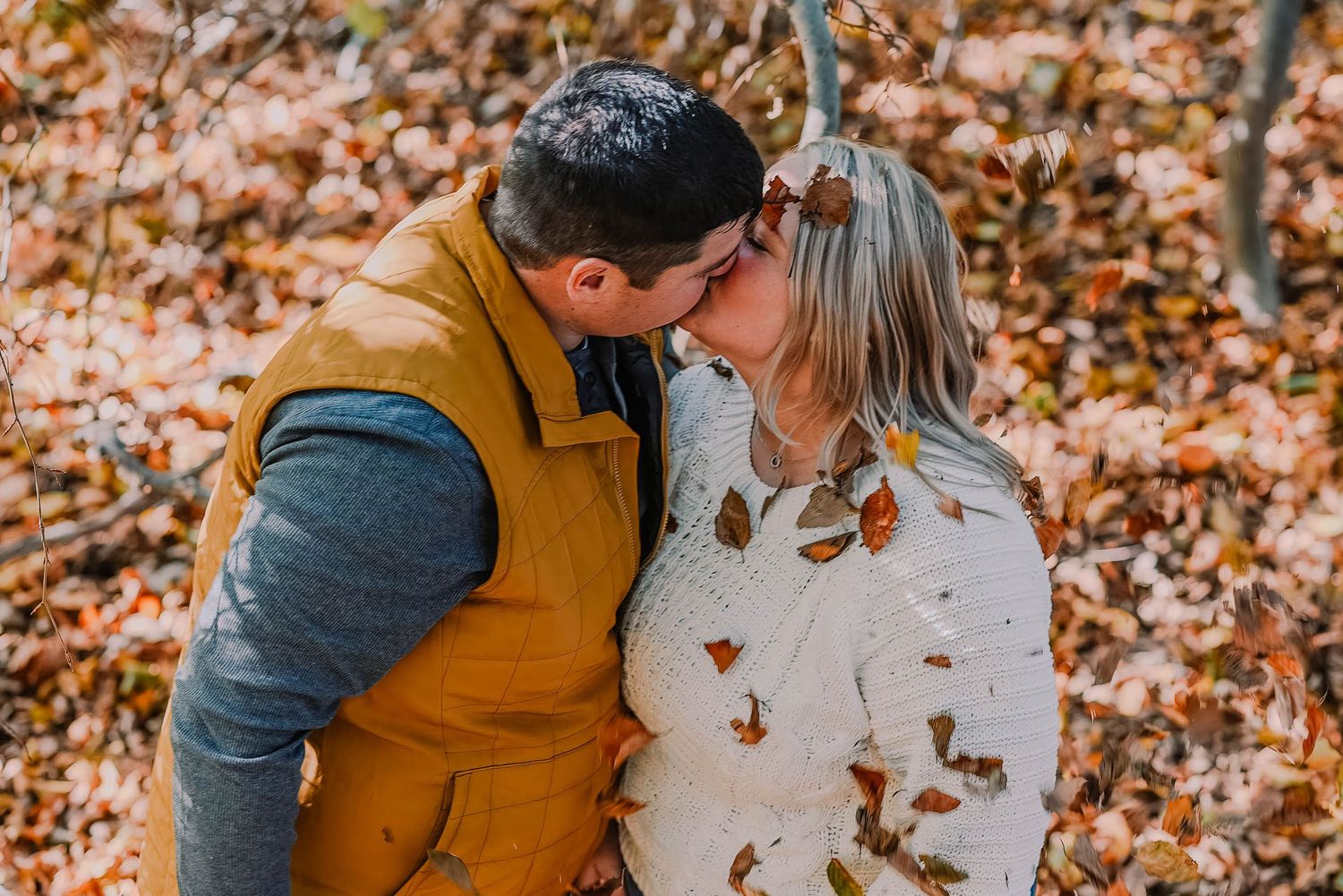 Couple in matching mustard and cream sweaters embrace during a fall photoshoot.