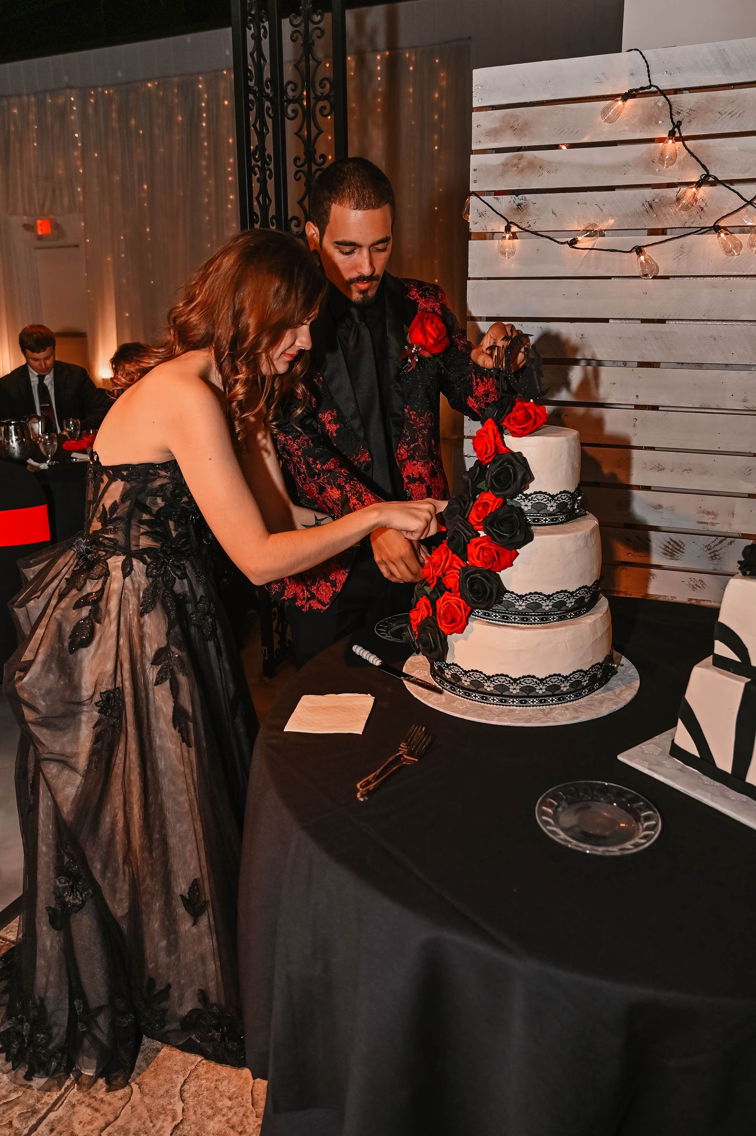 Wedding couple cutting their black and white tiered cake together at reception.