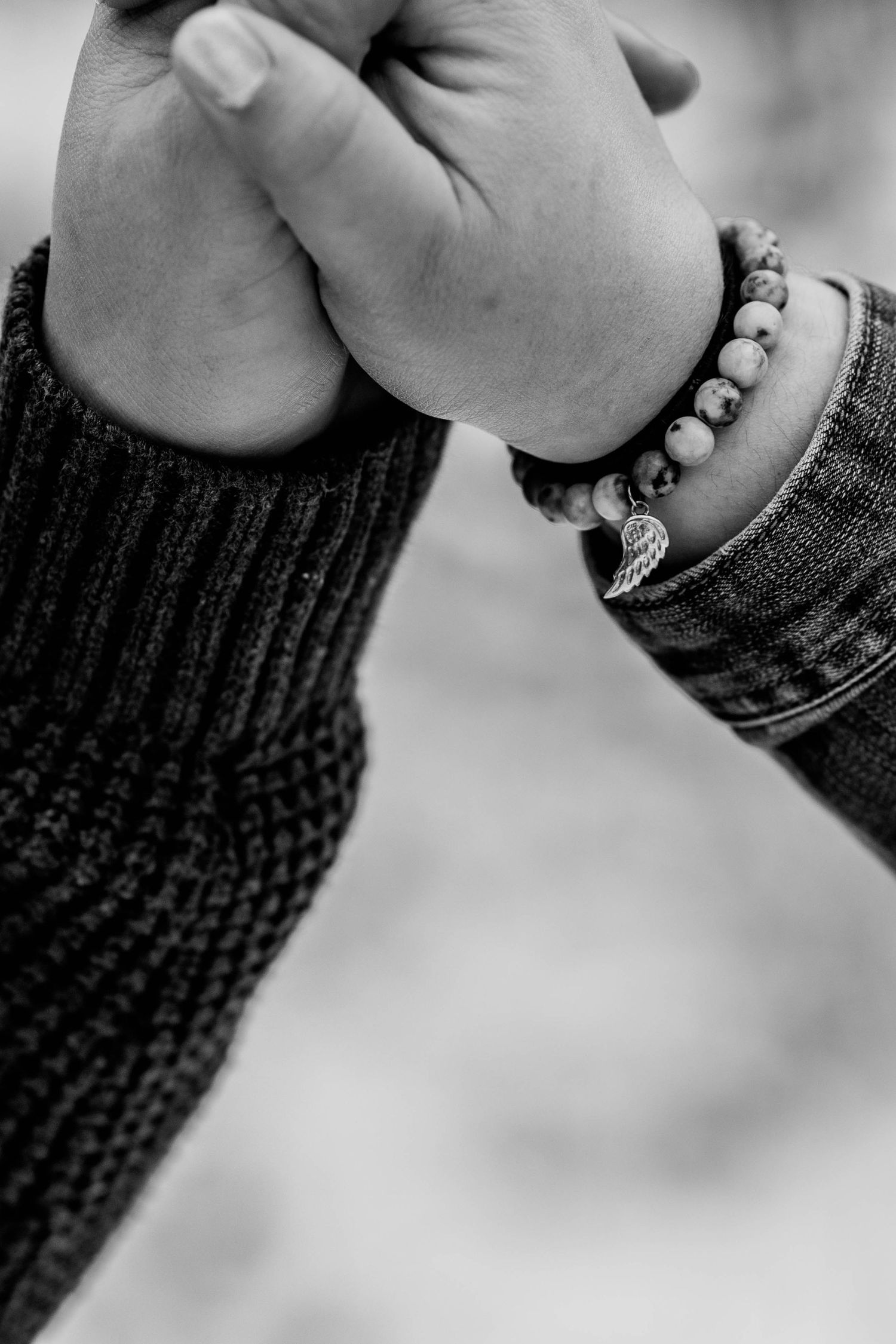 Close-up of hands wearing pearl bracelets in black and white.