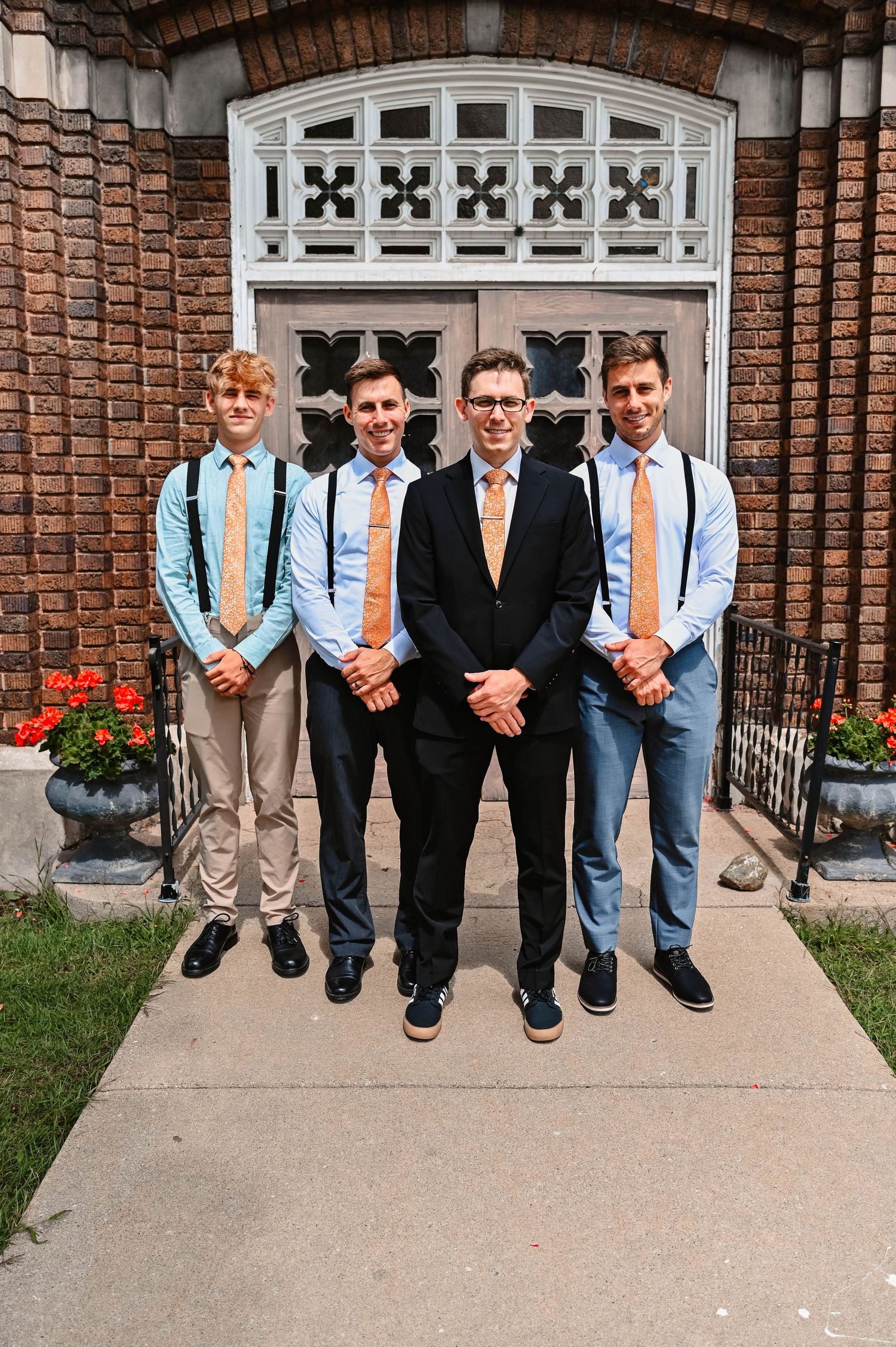 Row of groomsmen's legs and feet lined up on concrete steps.