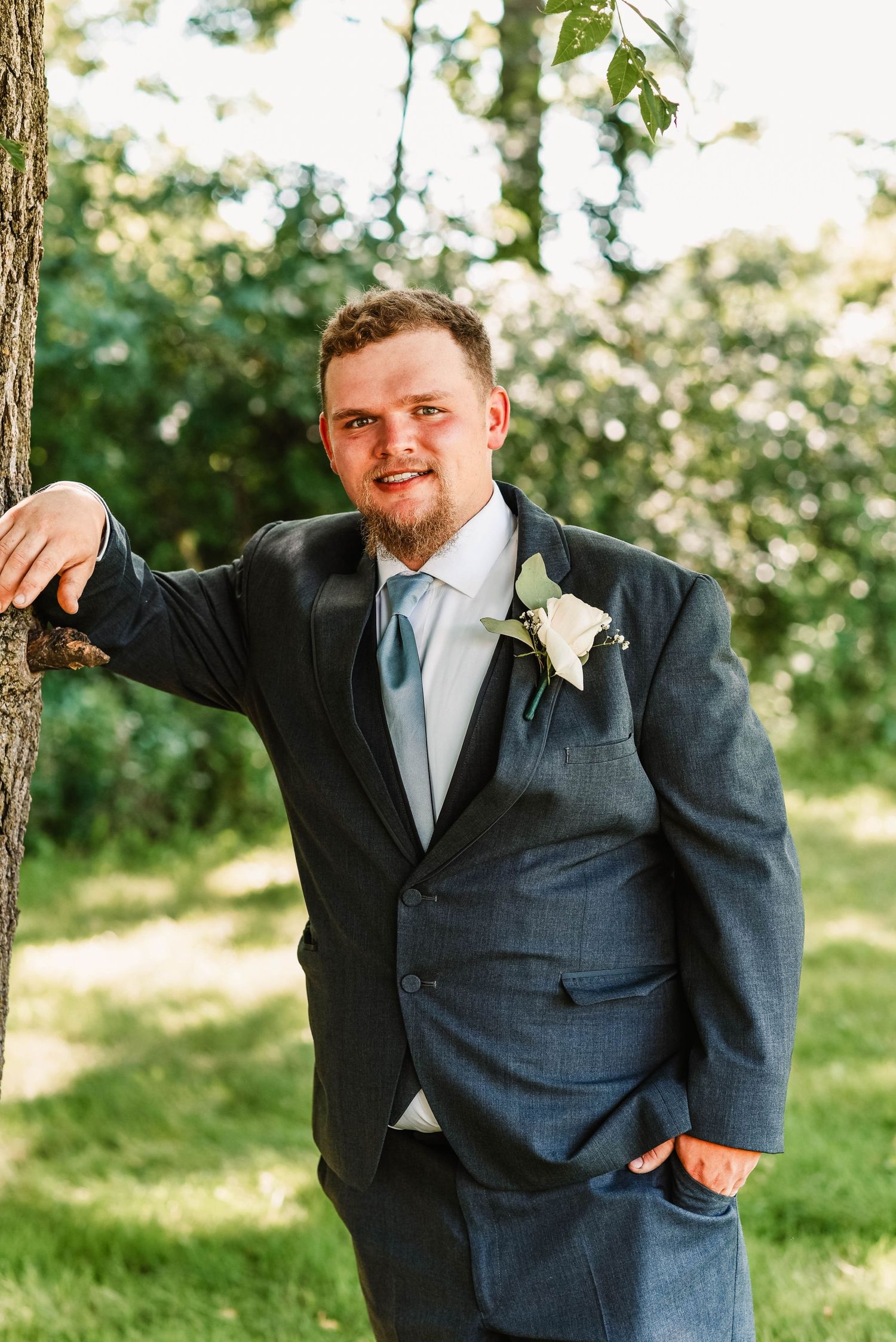 Groomsmen in suits share candid moments during an outdoor wedding photoshoot.