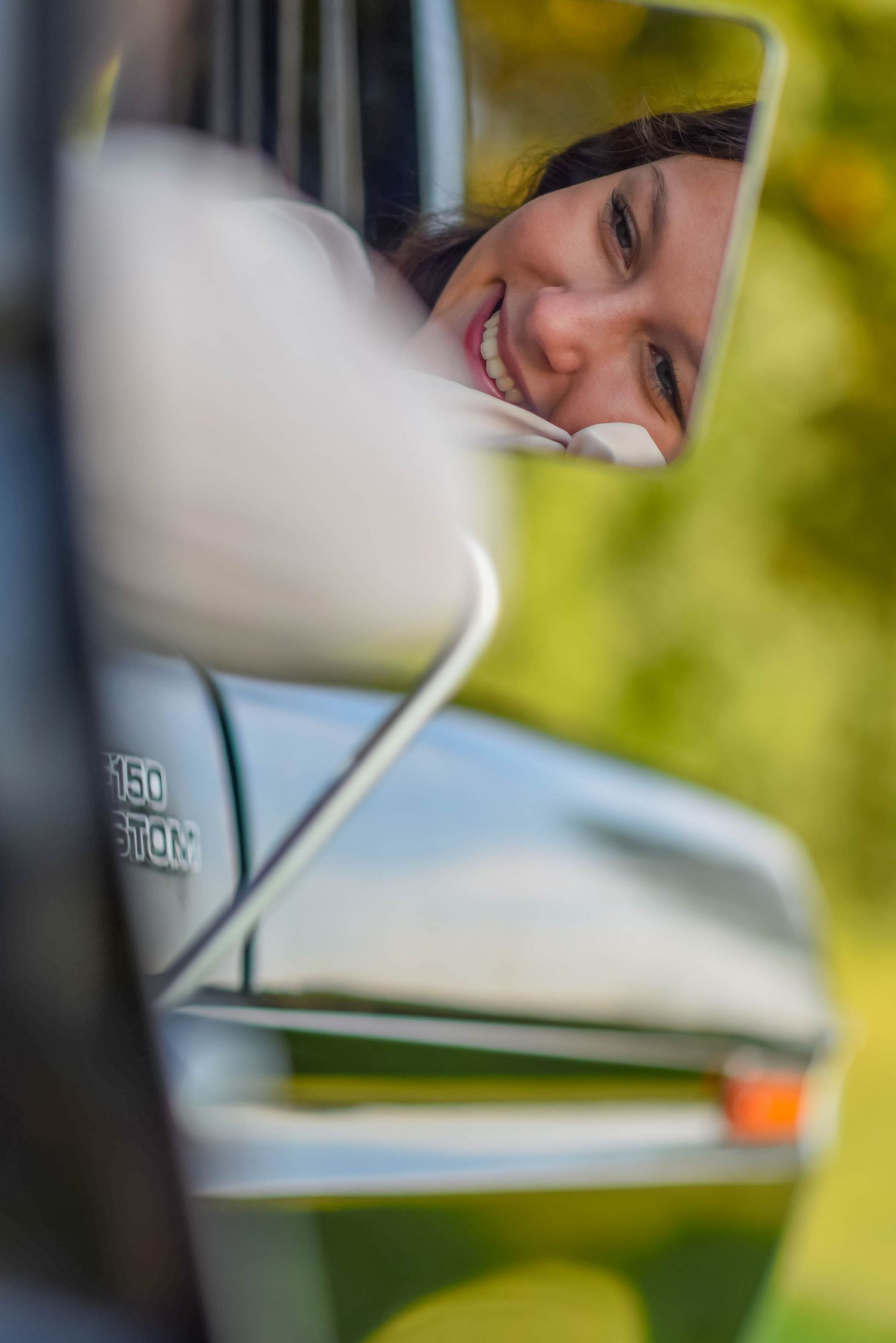 Creative wedding photo taken through car window with natural bokeh effect.