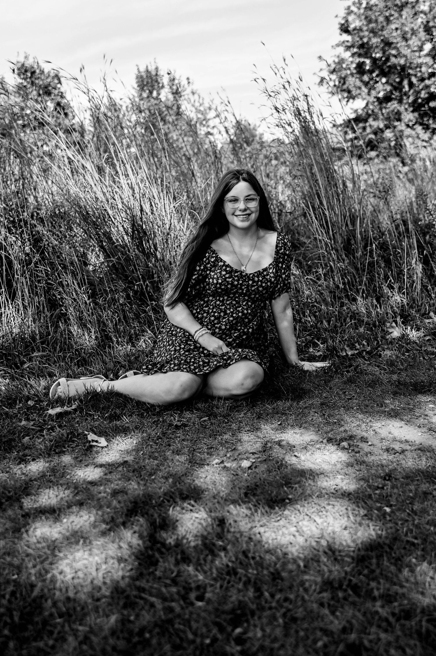 Black and white portraits in polka dot dress laying in sunlit grass.
