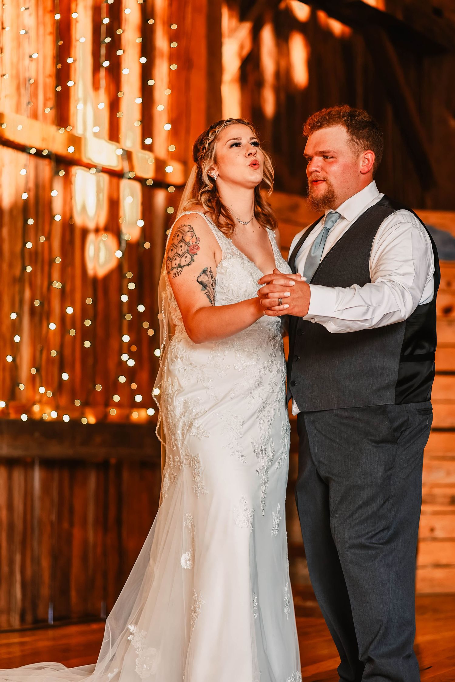 A romantic first dance at a rustic barn wedding illuminated by warm string lights.