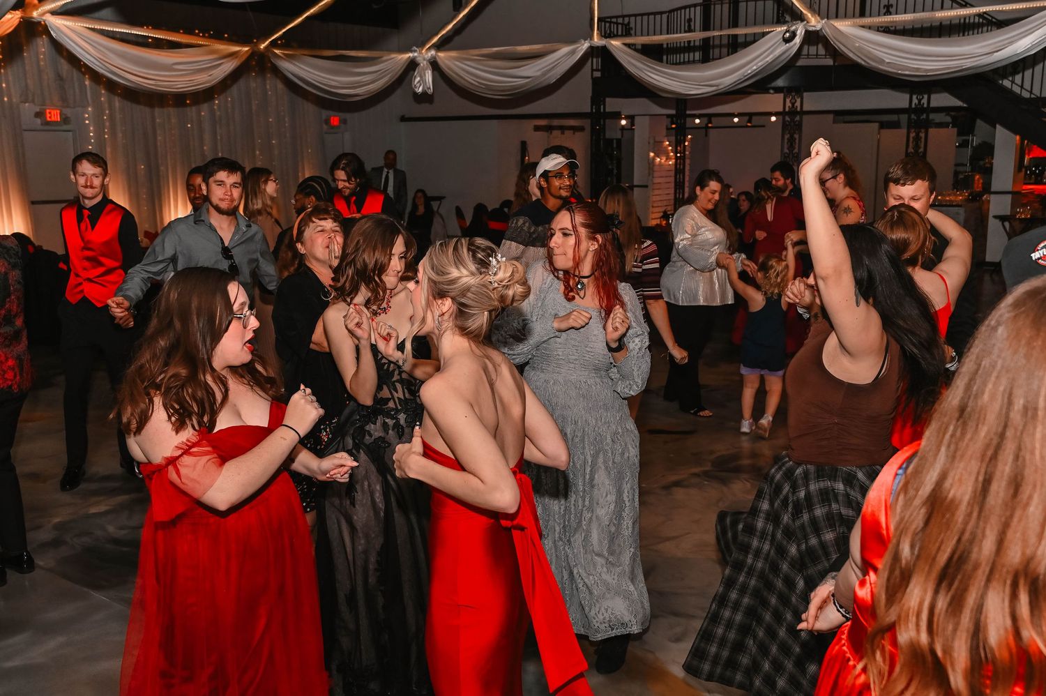 People dancing and celebrating at a party with red lighting.