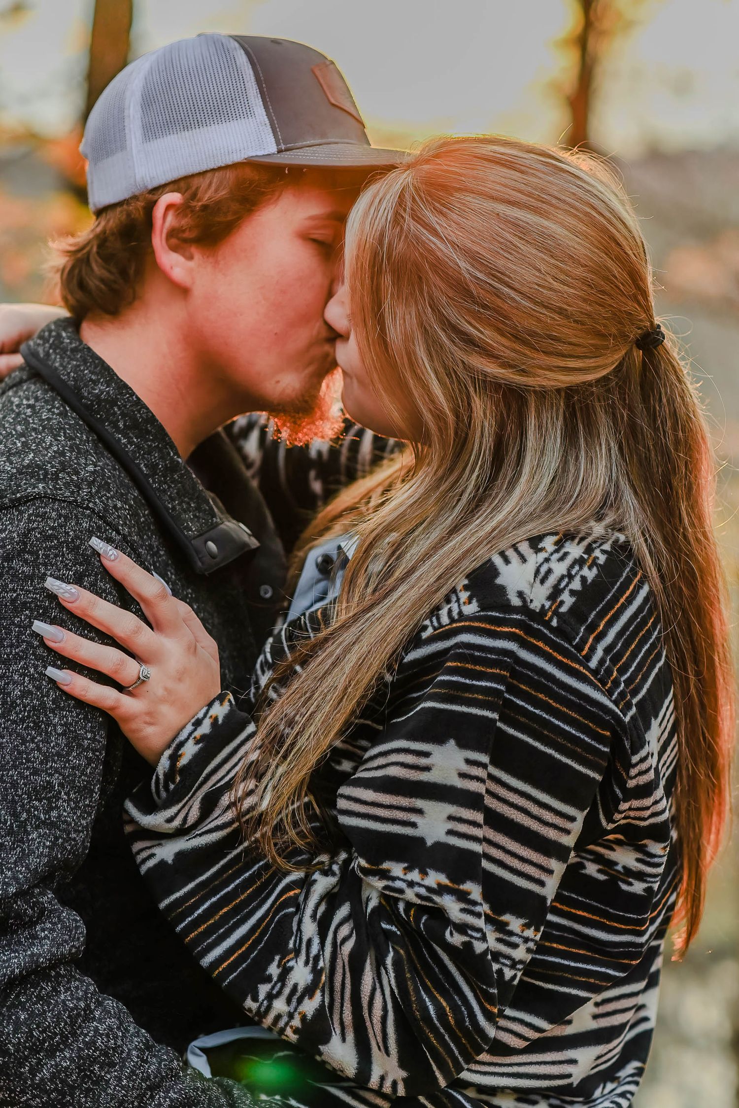 Couple sharing intimate moment at sunset wearing casual winter clothing.