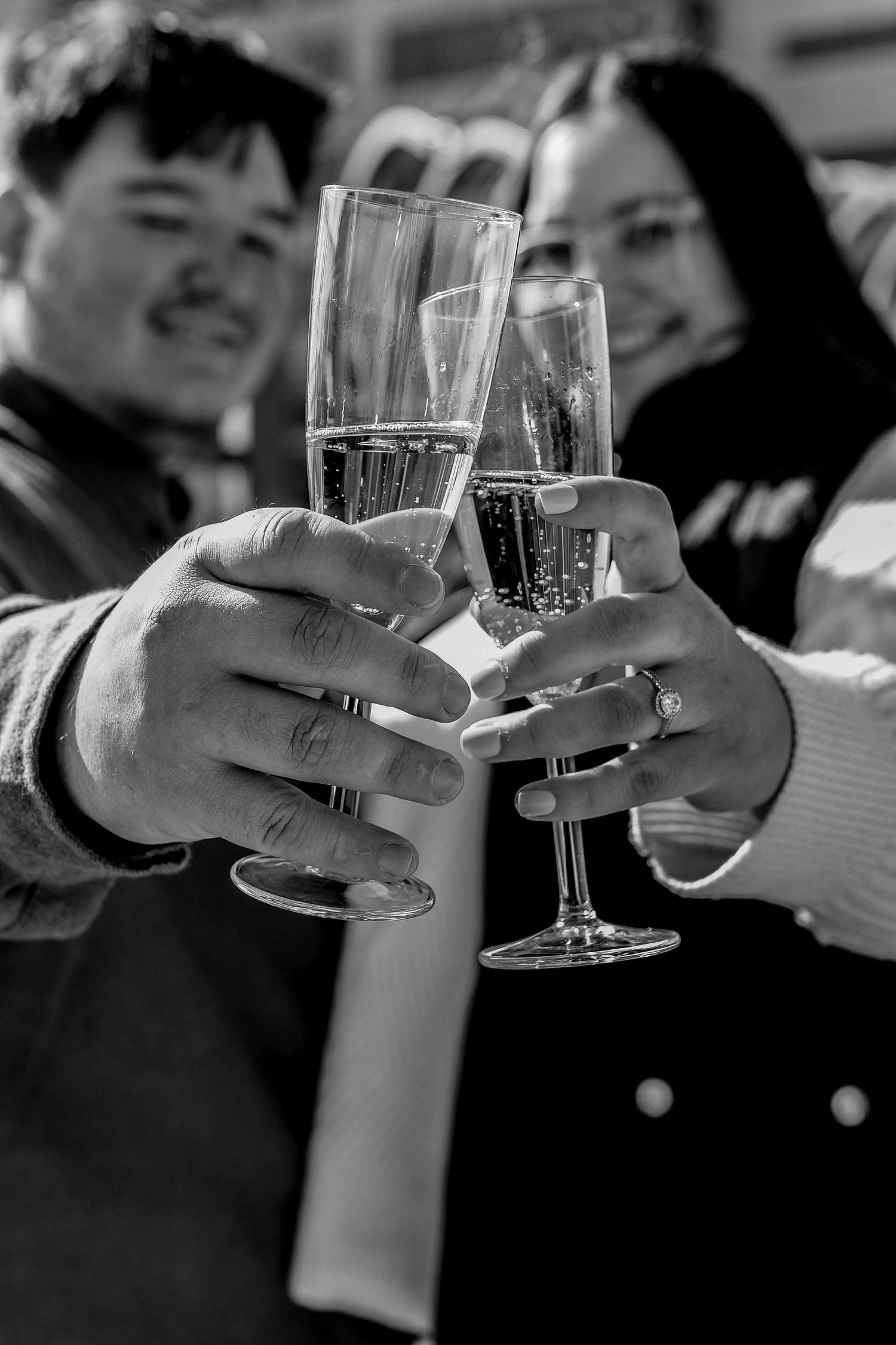 Black and white photo of hands toasting with champagne glasses.