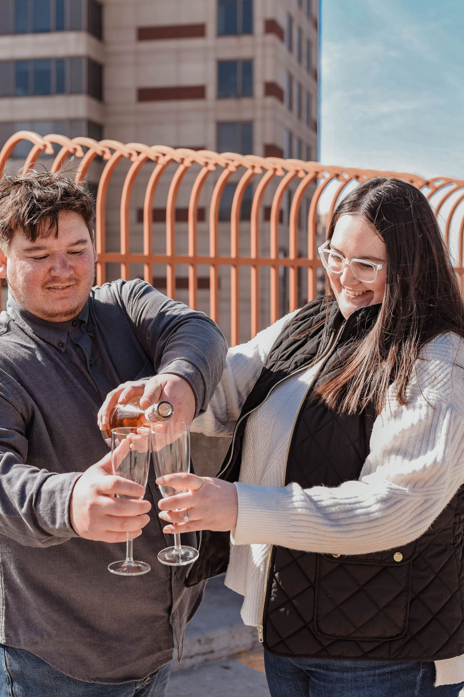 A happy couple celebrates with champagne while enjoying a sunny day in the city.